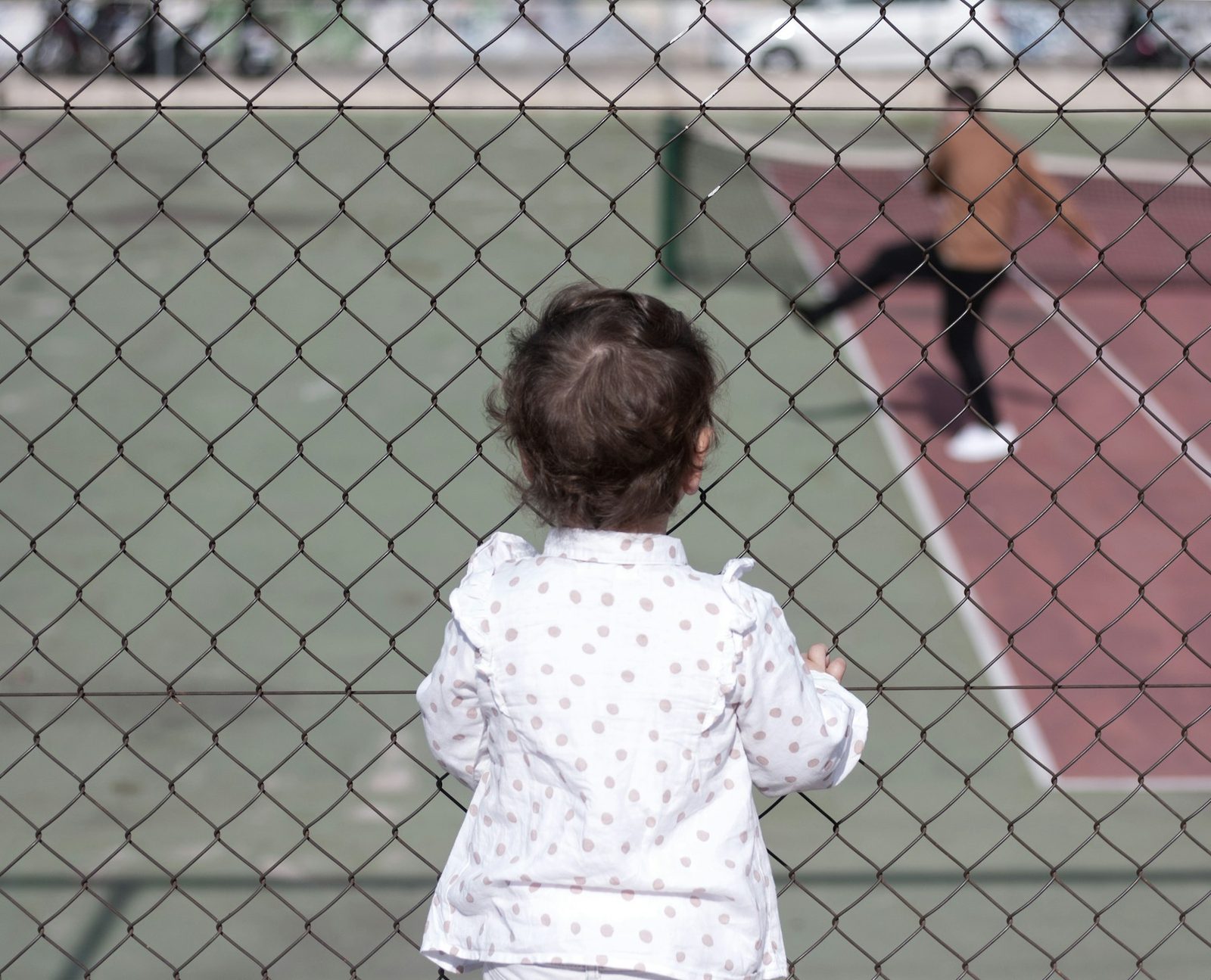 A young girl standing on a tennis court holding a racquet