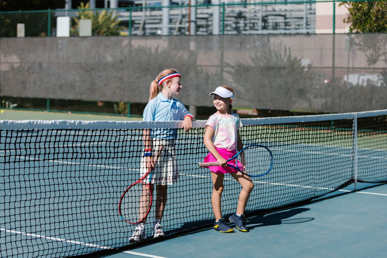 Two young players talking at the net during a break on an outdoor court