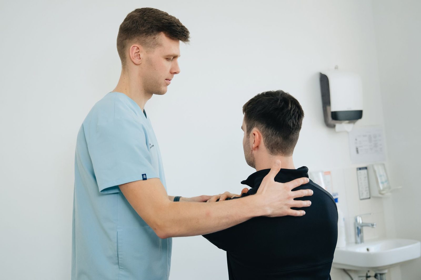 A physiotherapist treating a patient's shoulder in a clinic