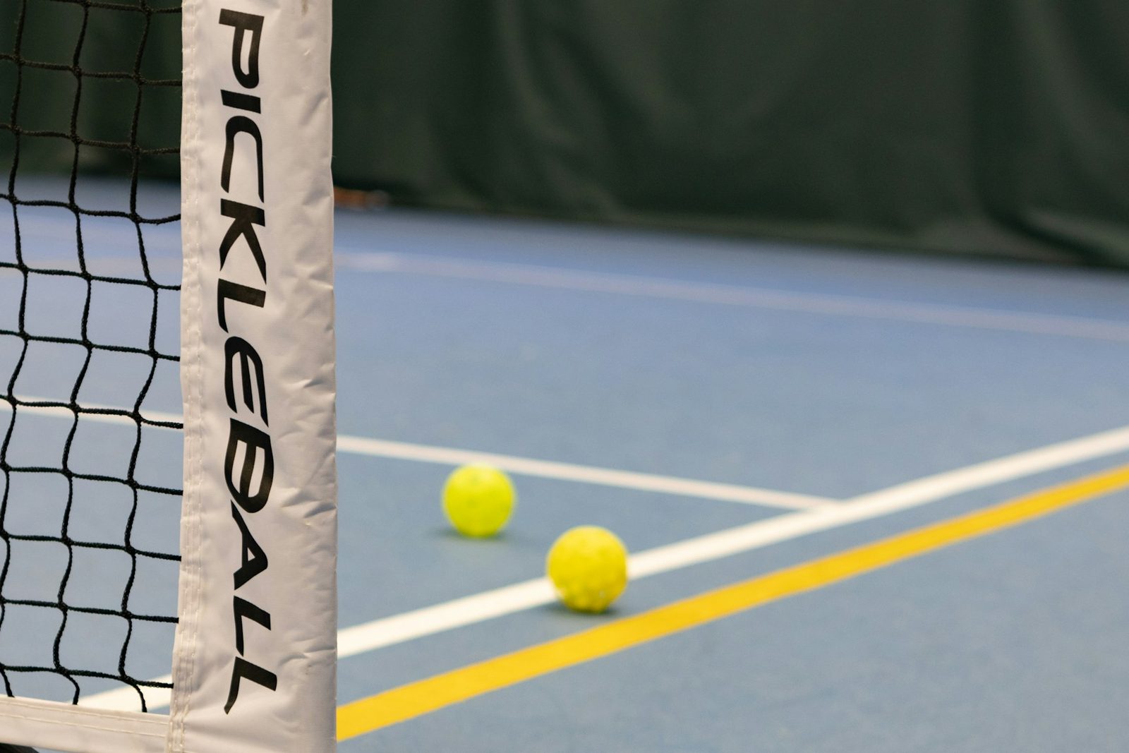 Three tennis balls on a tennis court beside the net