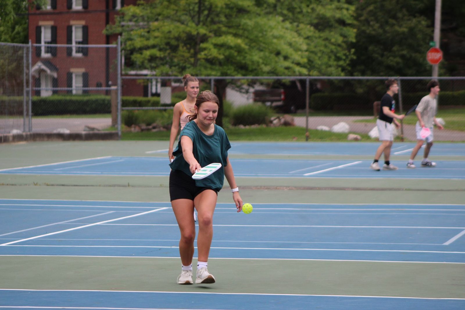 A group of adults playing pickleball on an outdoor court