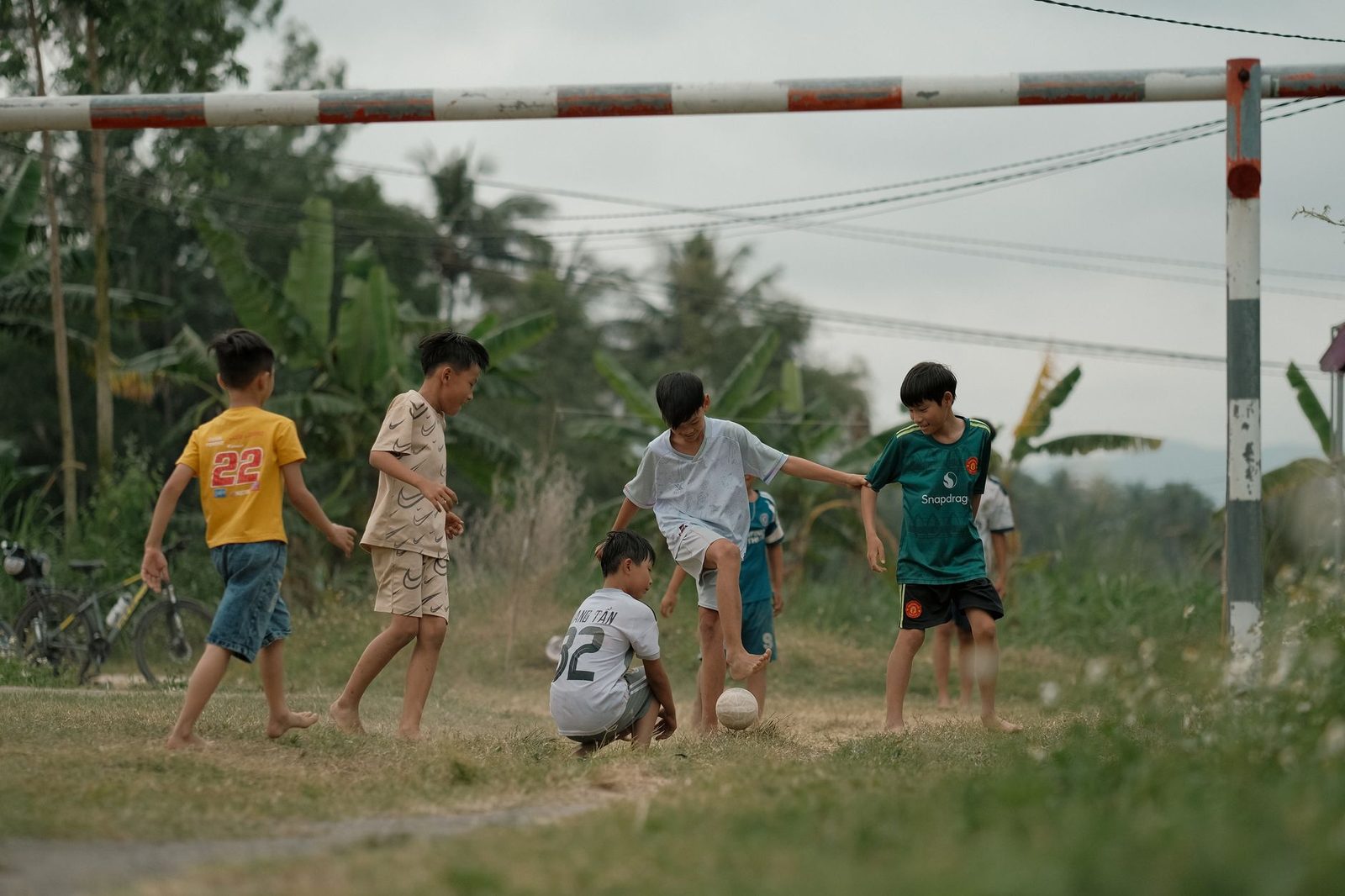 Group of boys playing football on a green field on a cloudy day