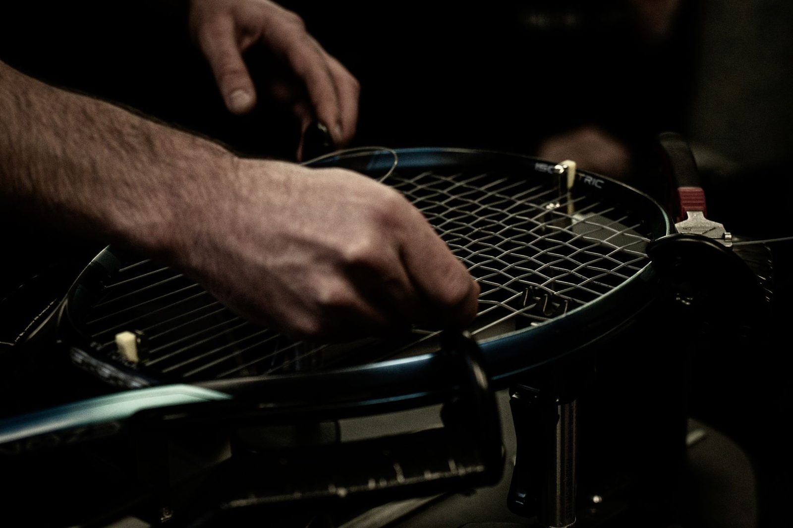 Close view of a tennis racquet being strung, showing the string pattern