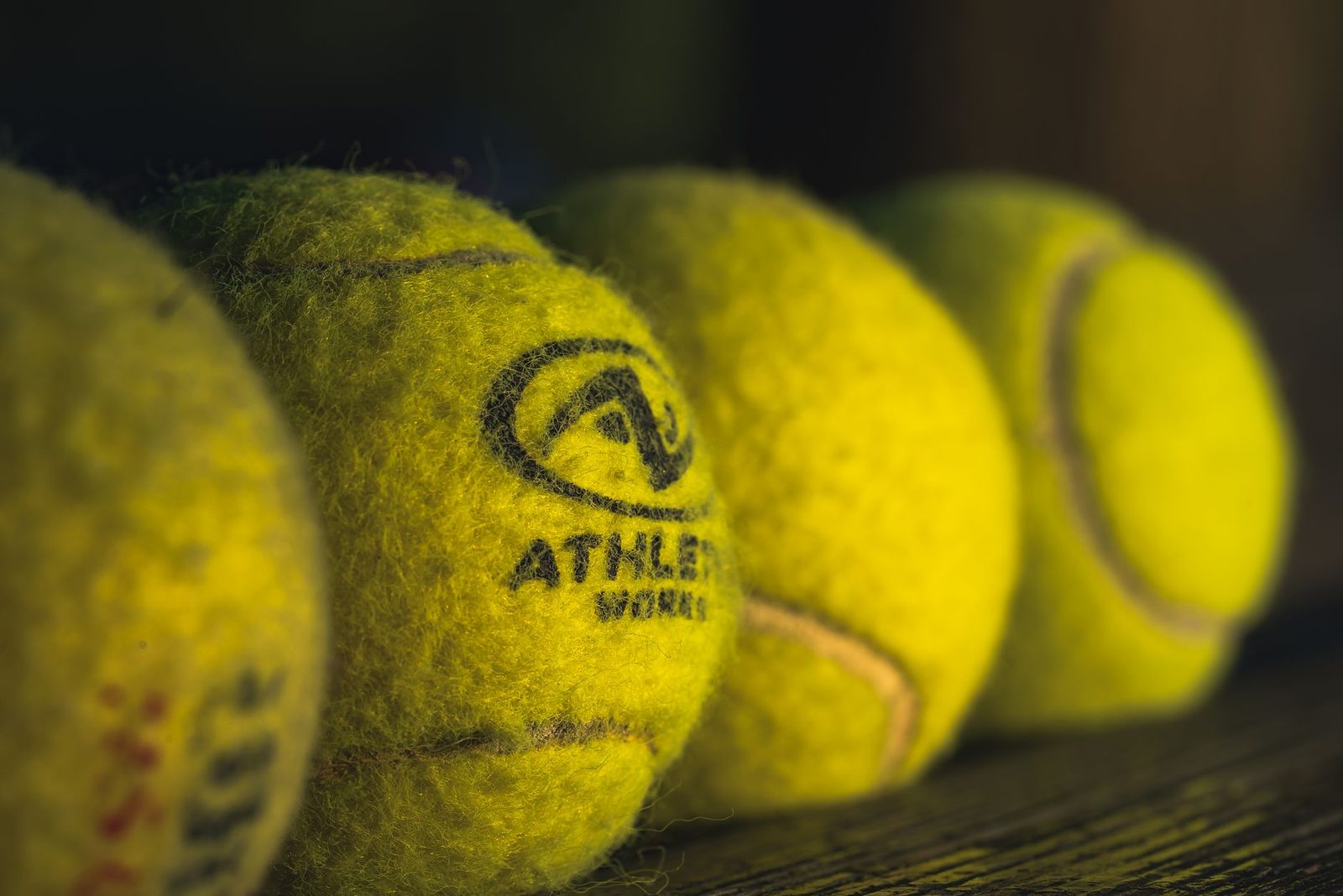 Yellow tennis balls resting on a wooden surface