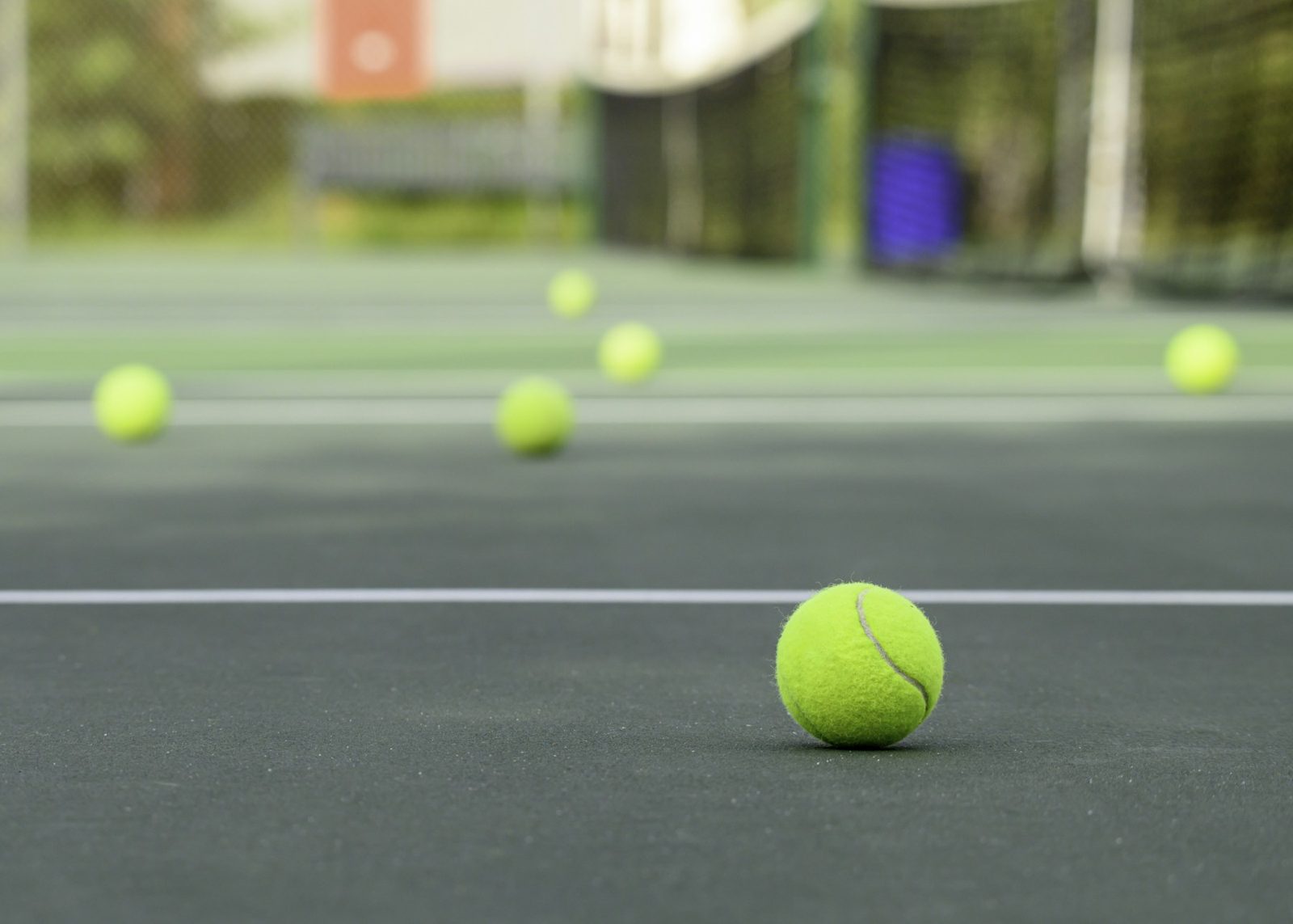 A tennis ball on court with the net behind it