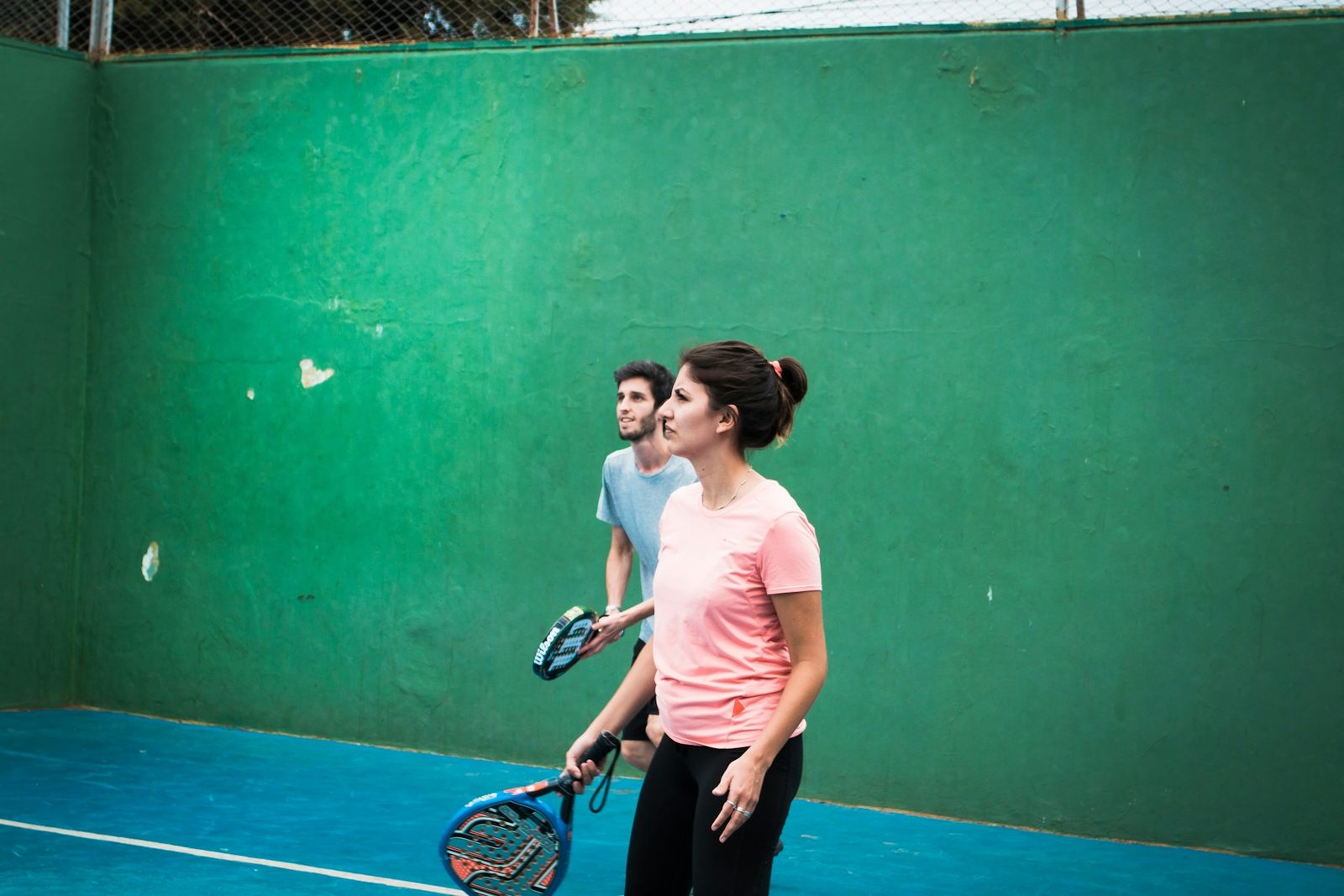 Two people standing on a tennis court holding racquets