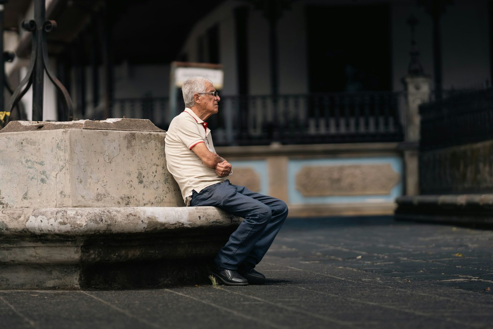 An older man sitting on a stone bench outdoors