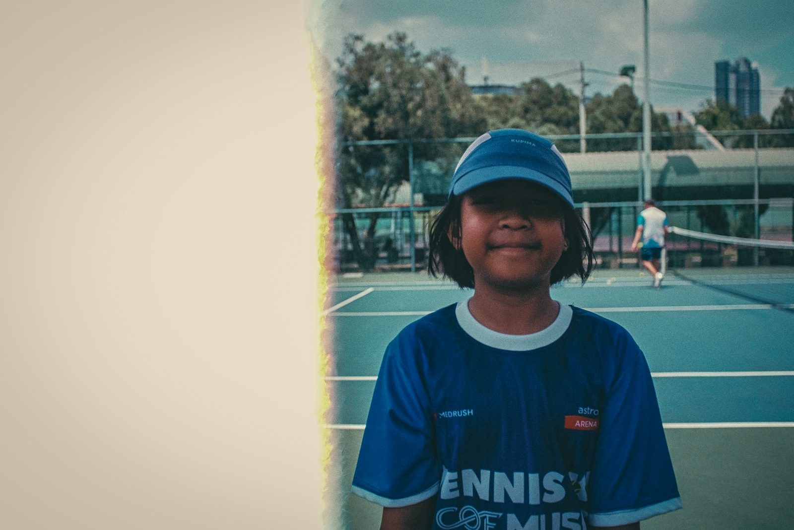 A young boy standing on a tennis court holding a racquet