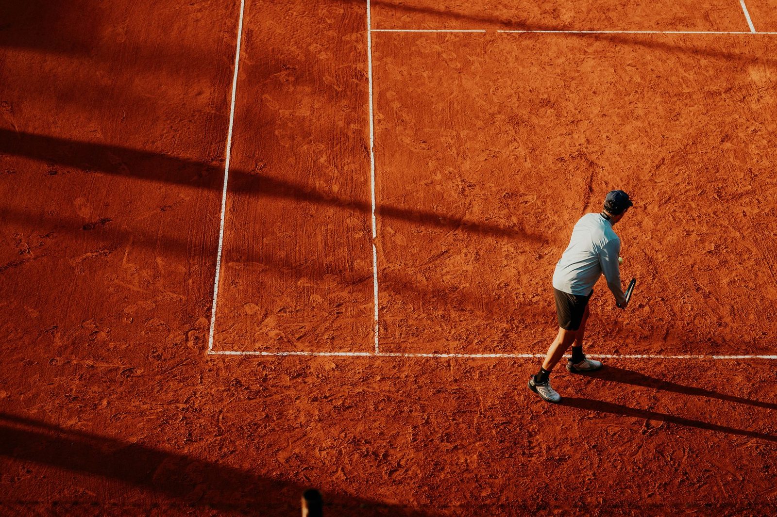 A tennis player preparing to serve on a clay court