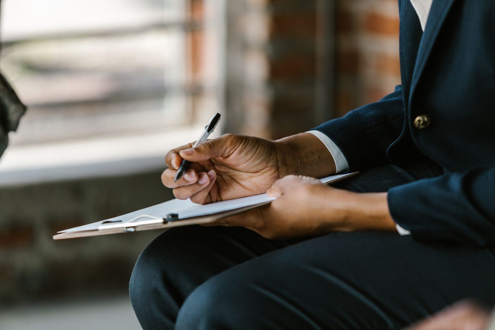 Close-up of a person writing results on a clipboard