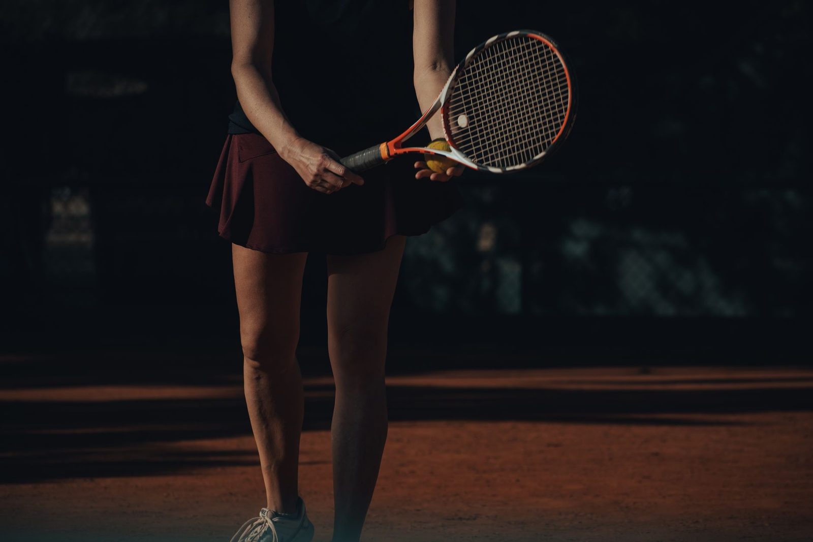 Female player ready to serve on a clay court, holding racquet and ball