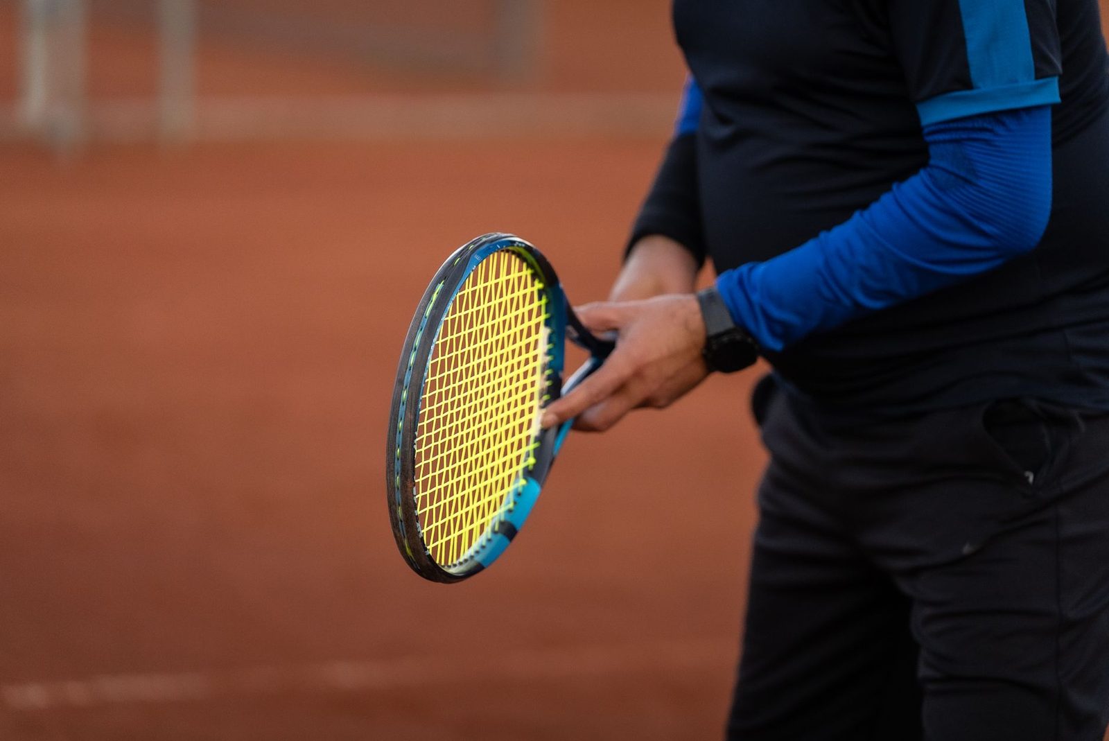 Close view of a tennis player holding a racquet on a clay court