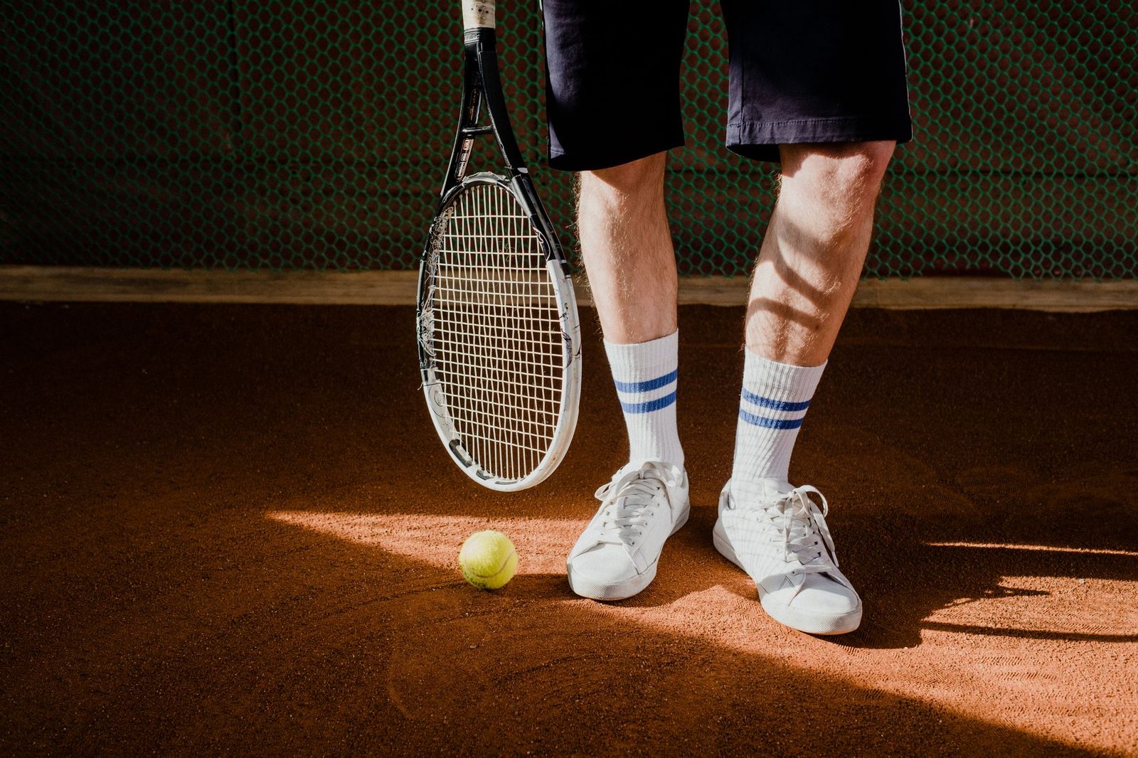 Close-up of a tennis player holding racquet and ball on a clay court