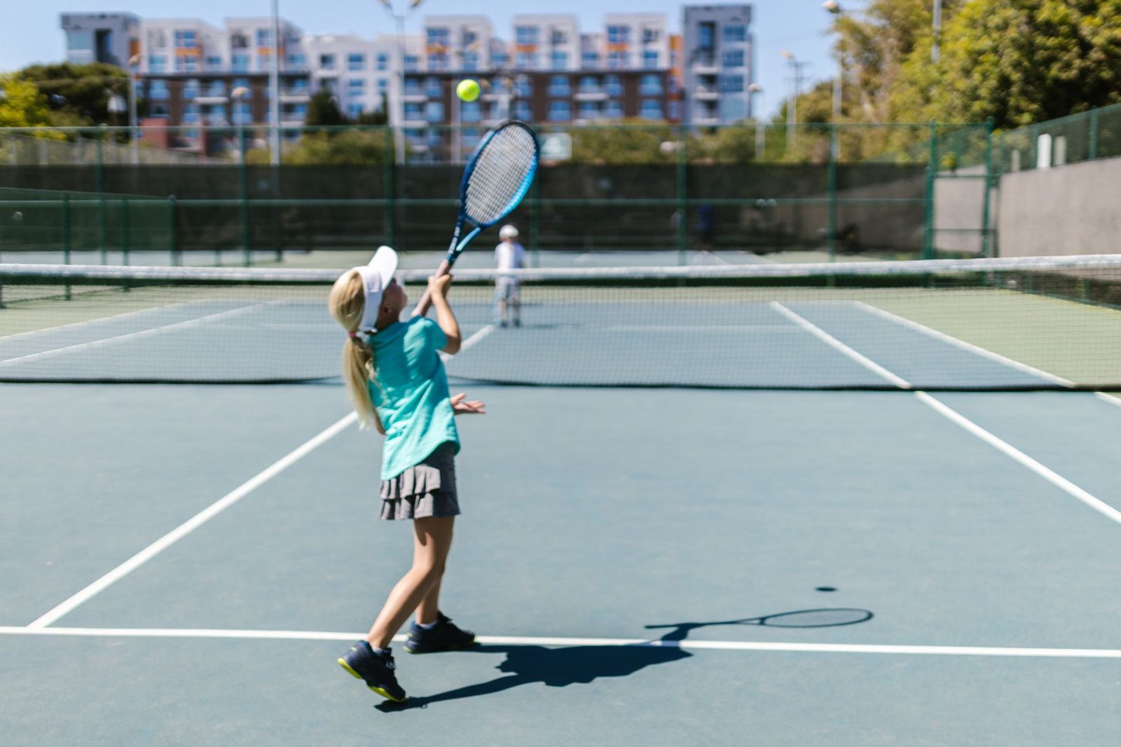 A girl in sportswear hitting a tennis ball on a sunny outdoor court