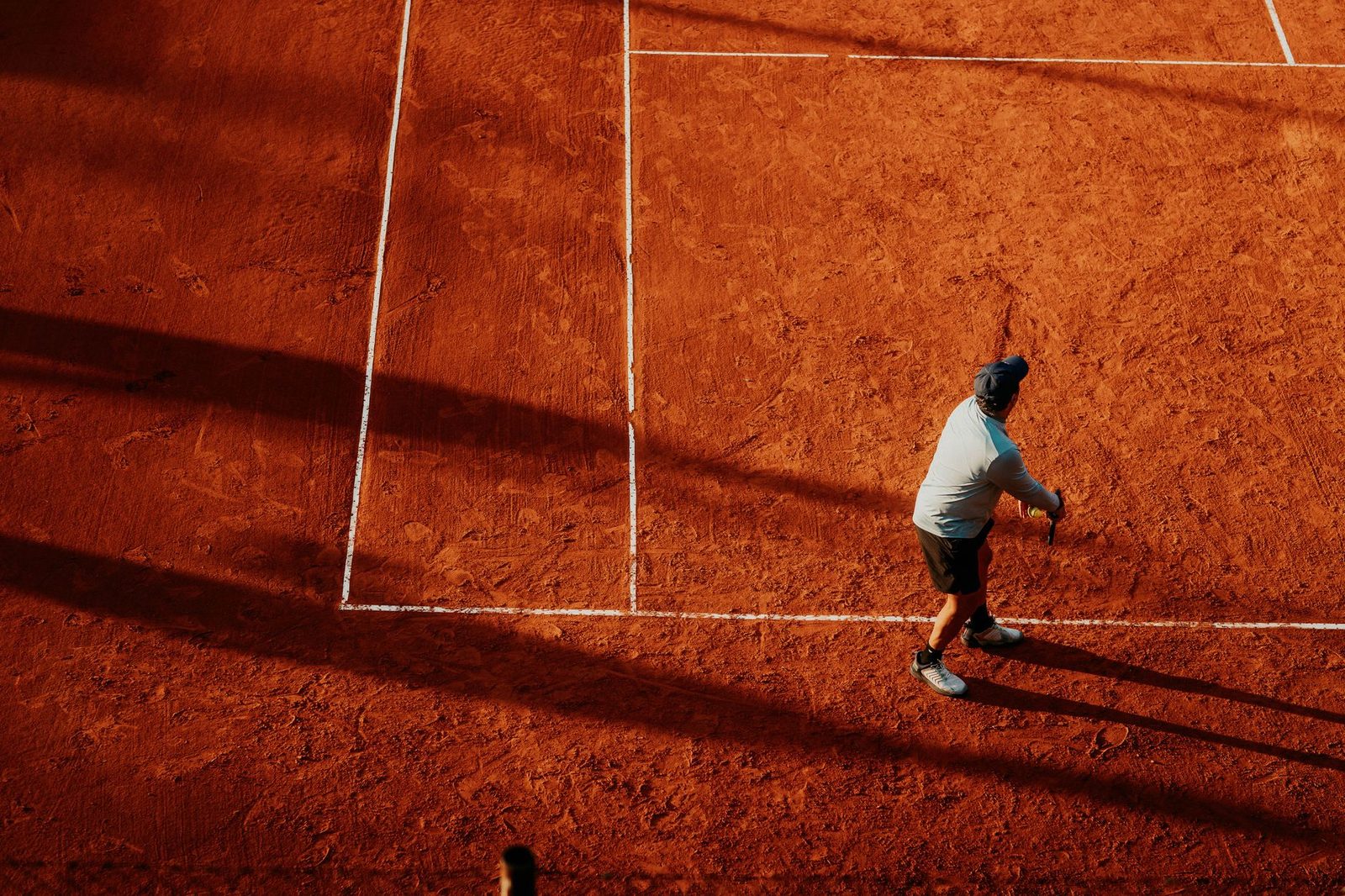 Overhead view of a tennis player serving on a clay court