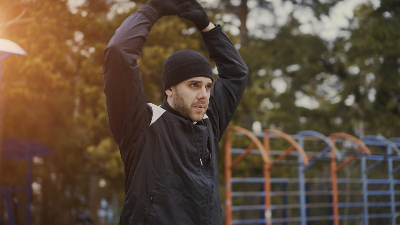 A man stretching outdoors with his arms raised