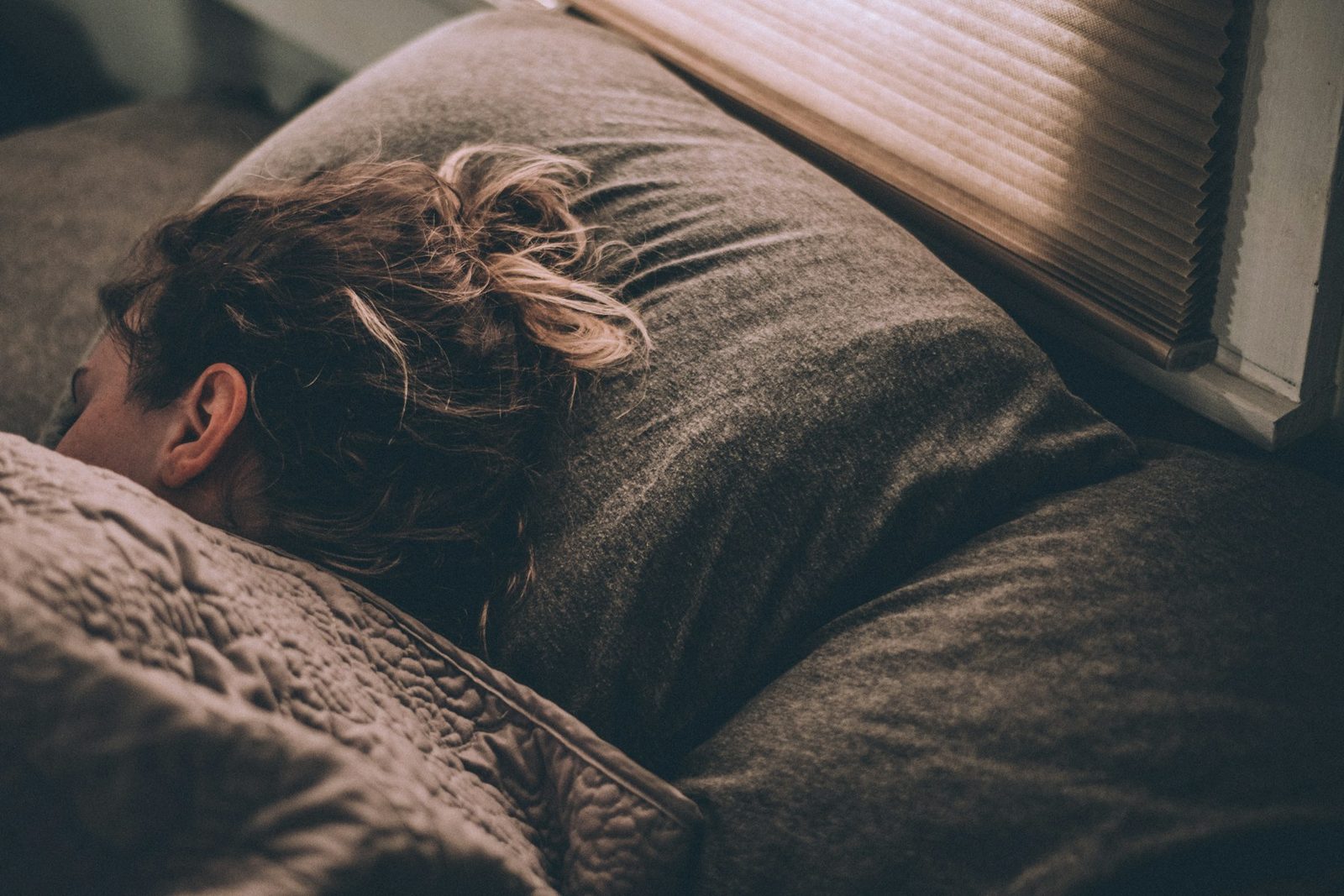 A woman sleeping in bed under blankets