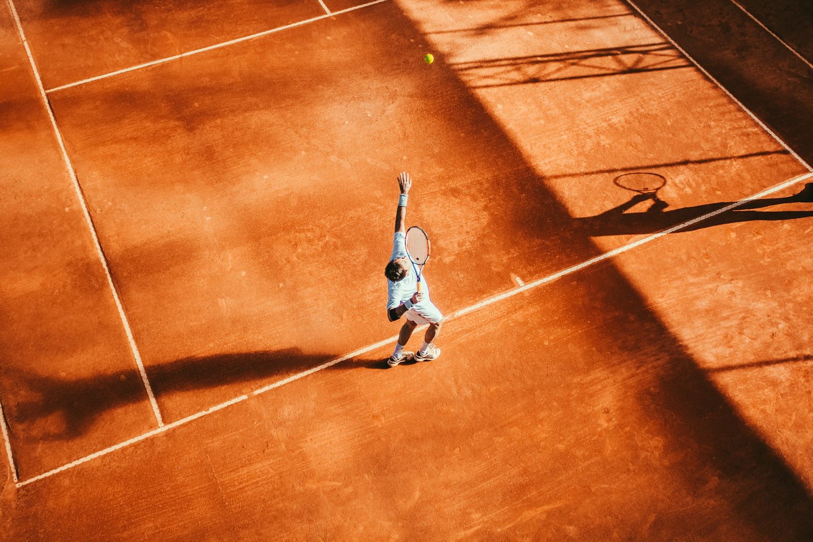 Player driving through a forehand groundstroke on an outdoor tennis court