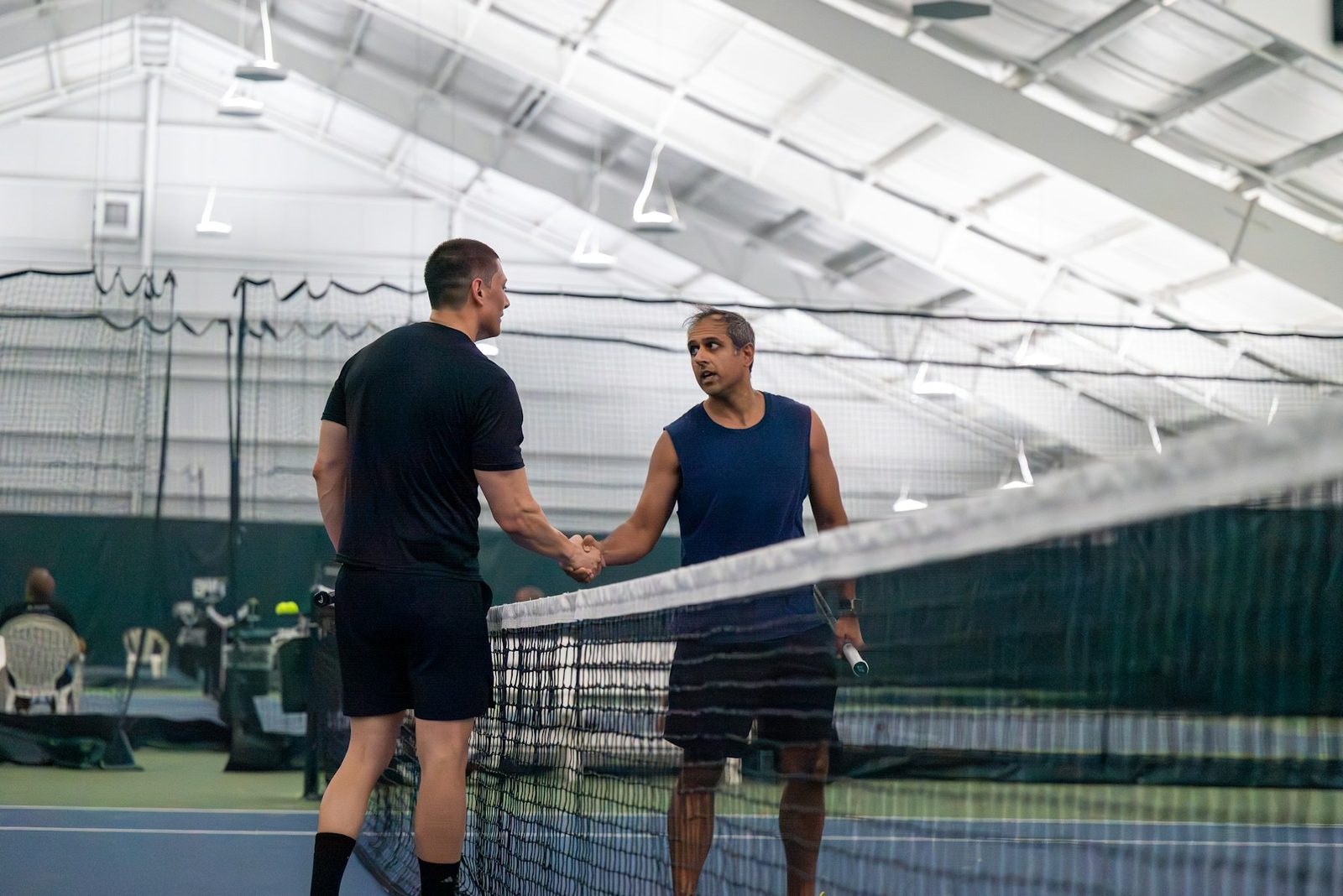 Two people shaking hands over a tennis net