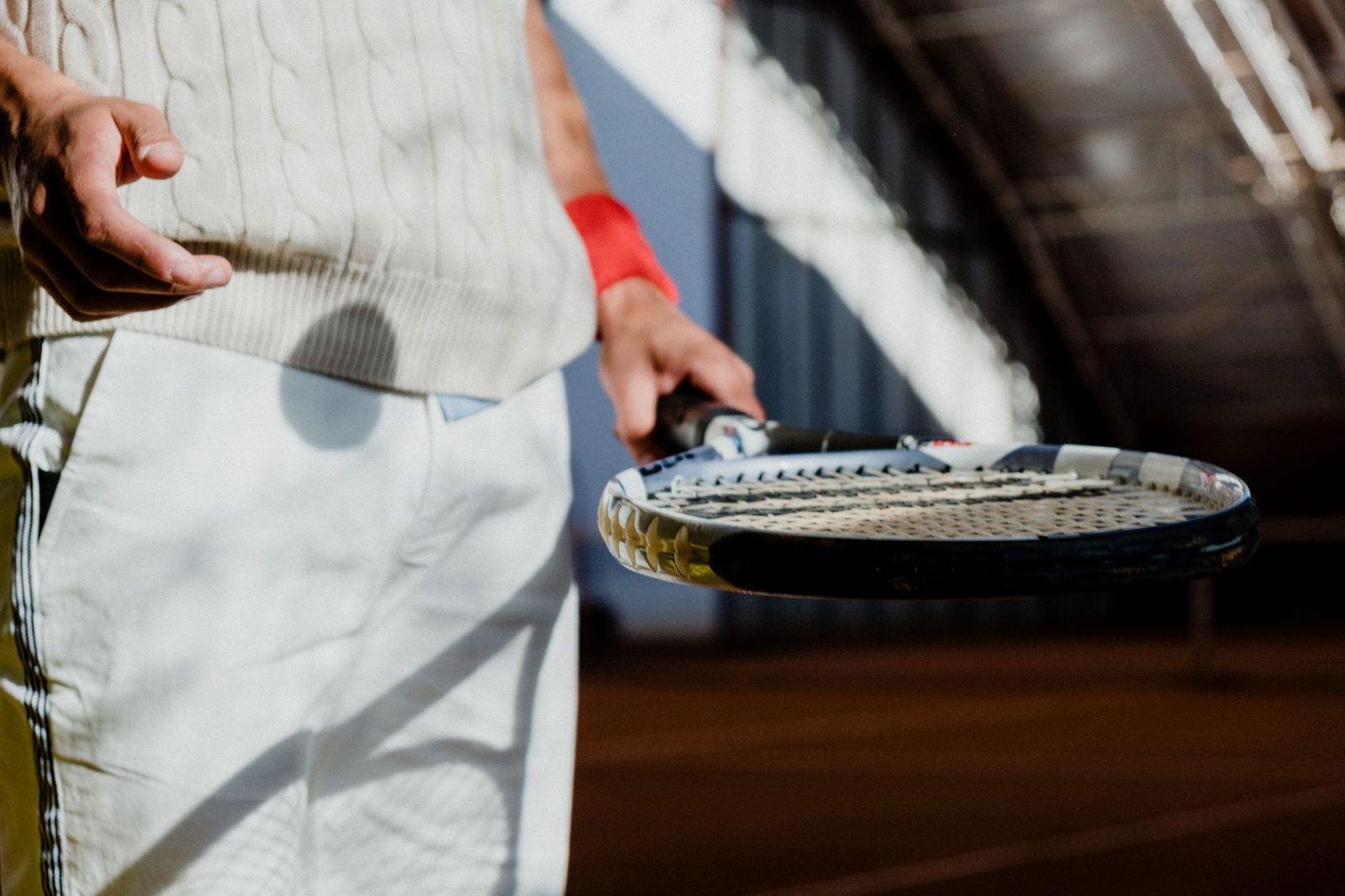 A man holding a tennis racquet on an indoor court, ready to play