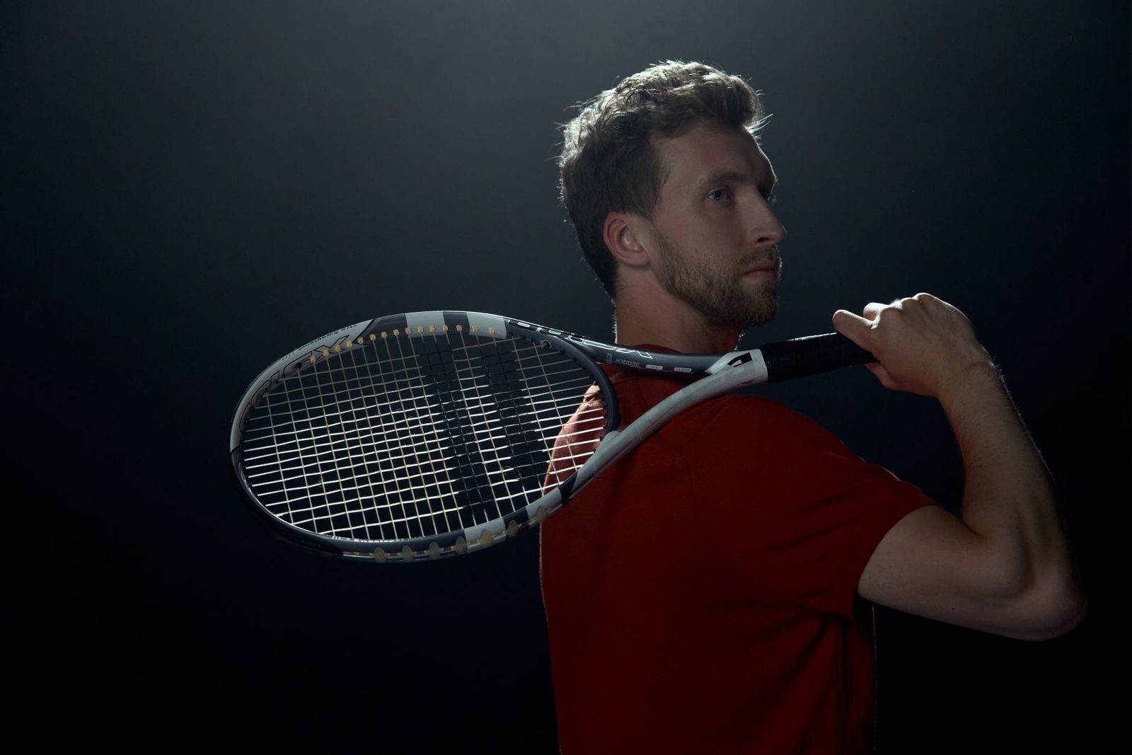 Portrait of a tennis player with a racquet against a dark background