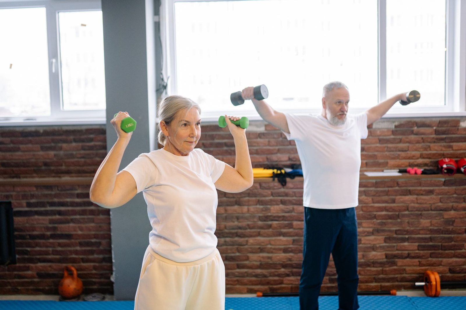An older man and woman working out with dumbbells