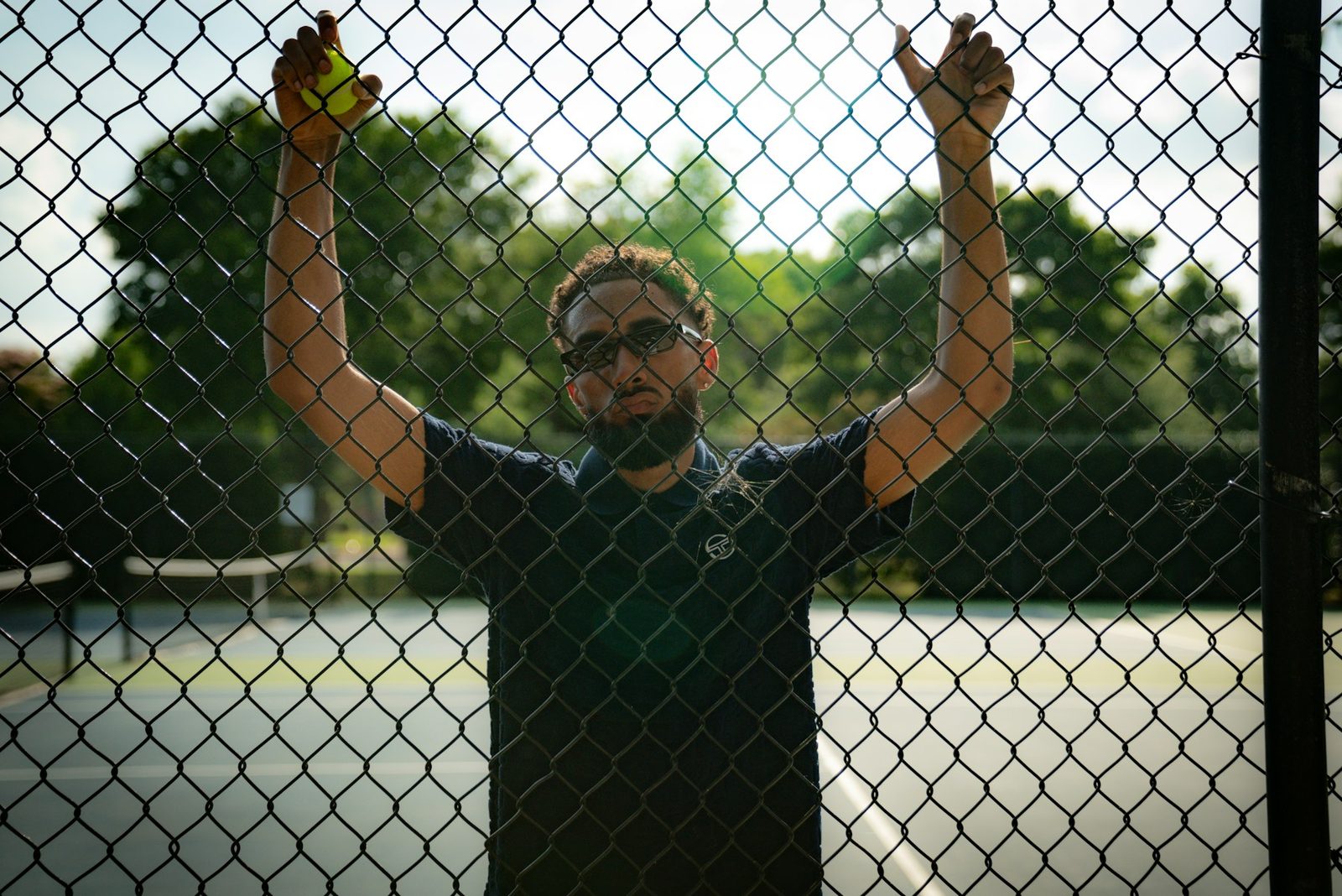 A man holding a tennis racquet behind a court fence