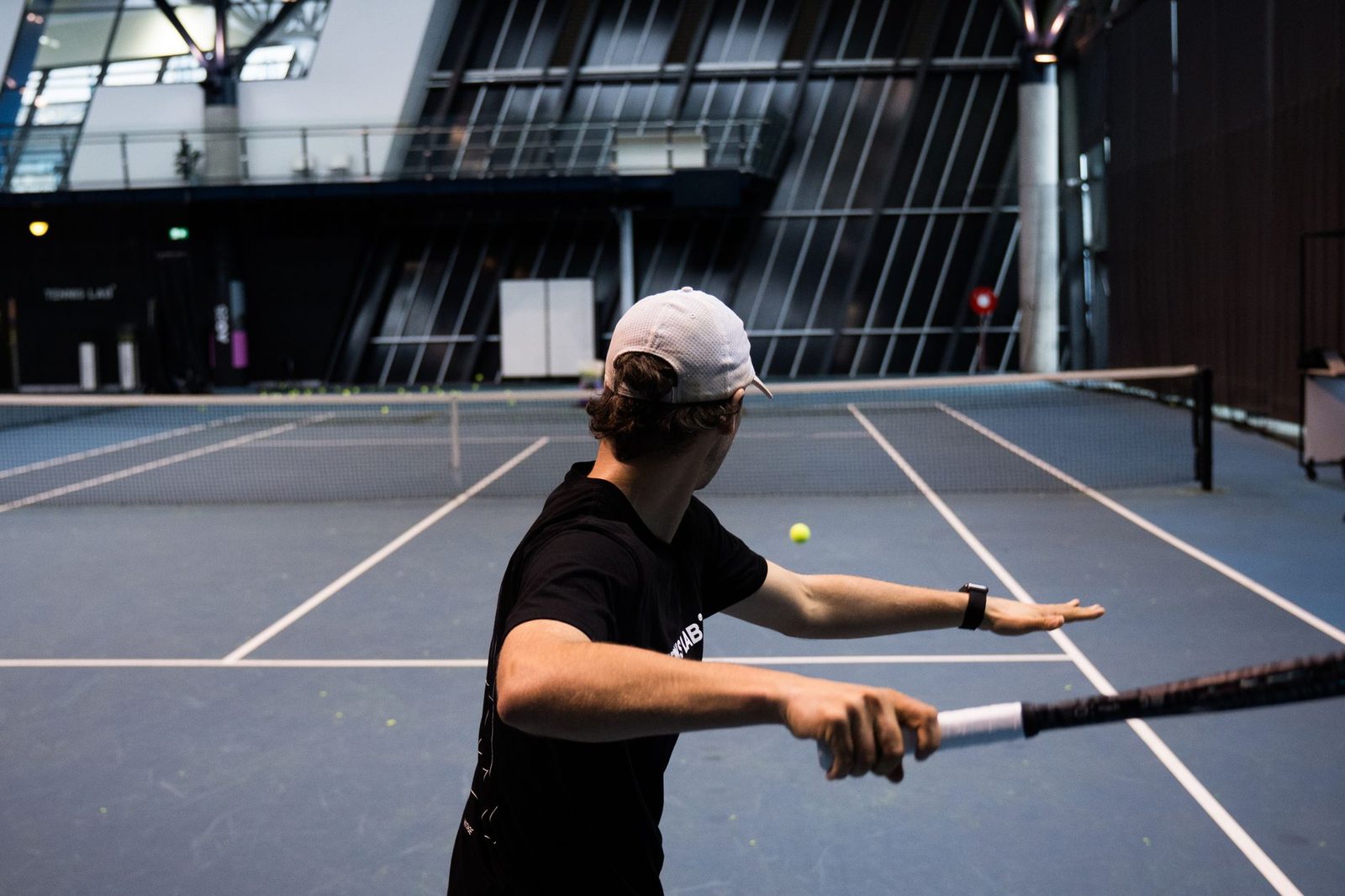 An indoor tennis scene with a player striking the ball