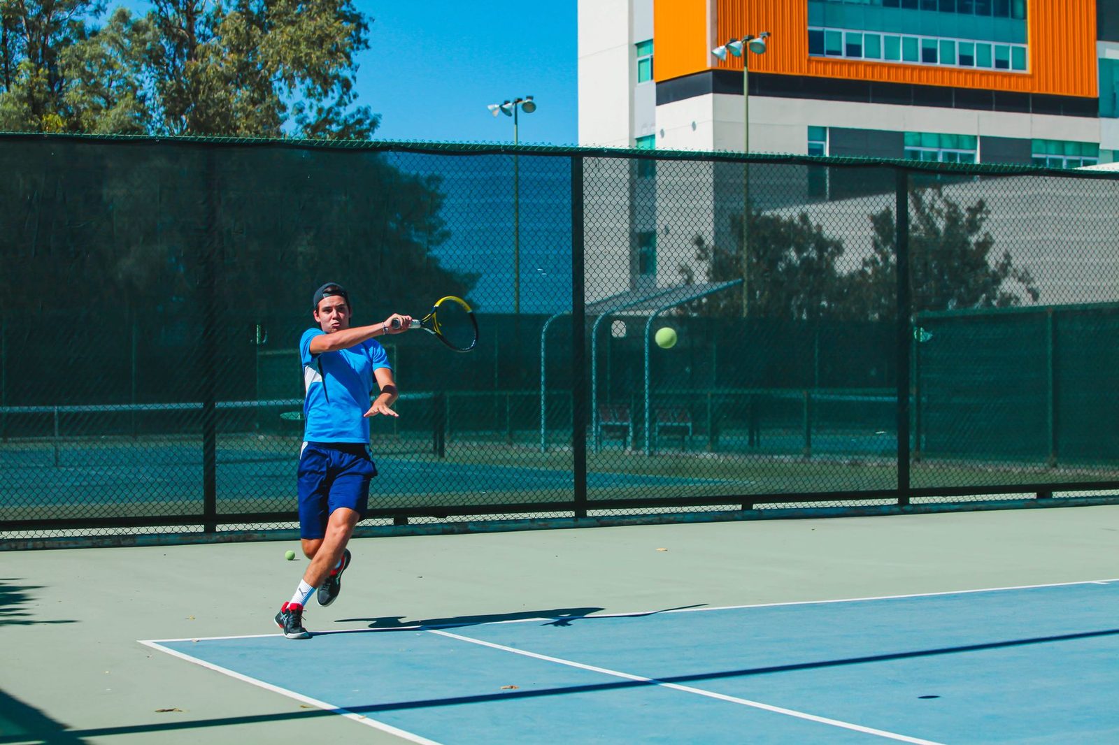An athletic man playing tennis outdoors on a sunny day