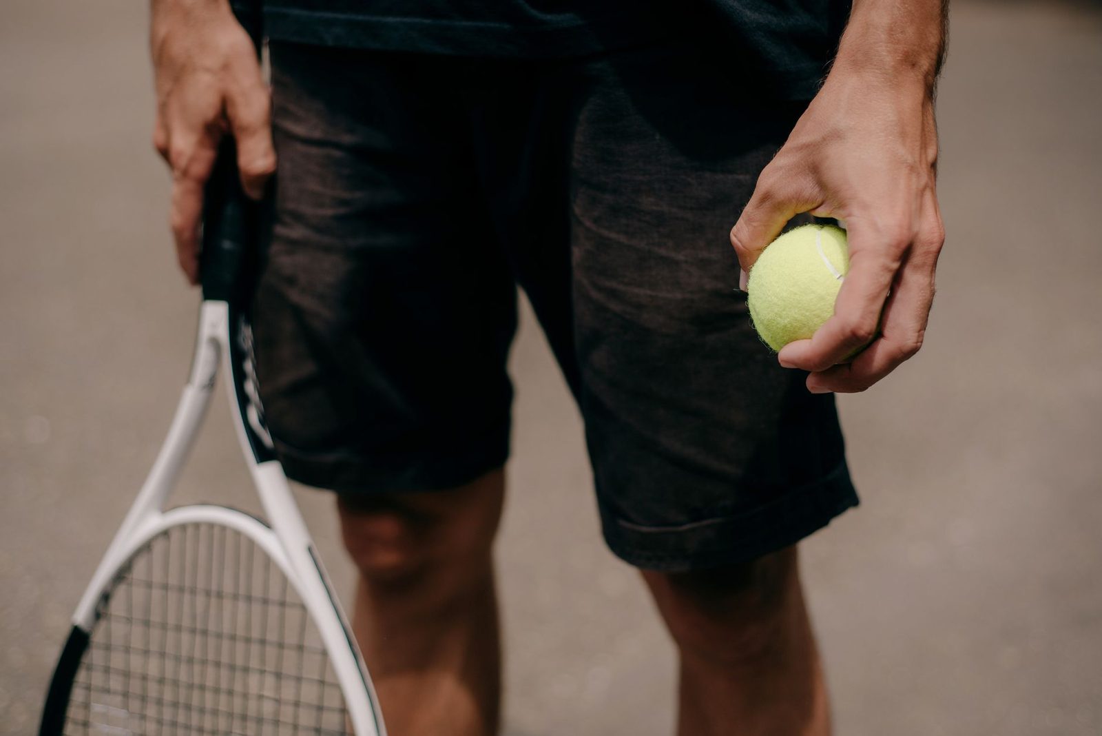 Close-up of a player holding a racquet and ball, ready to start hitting