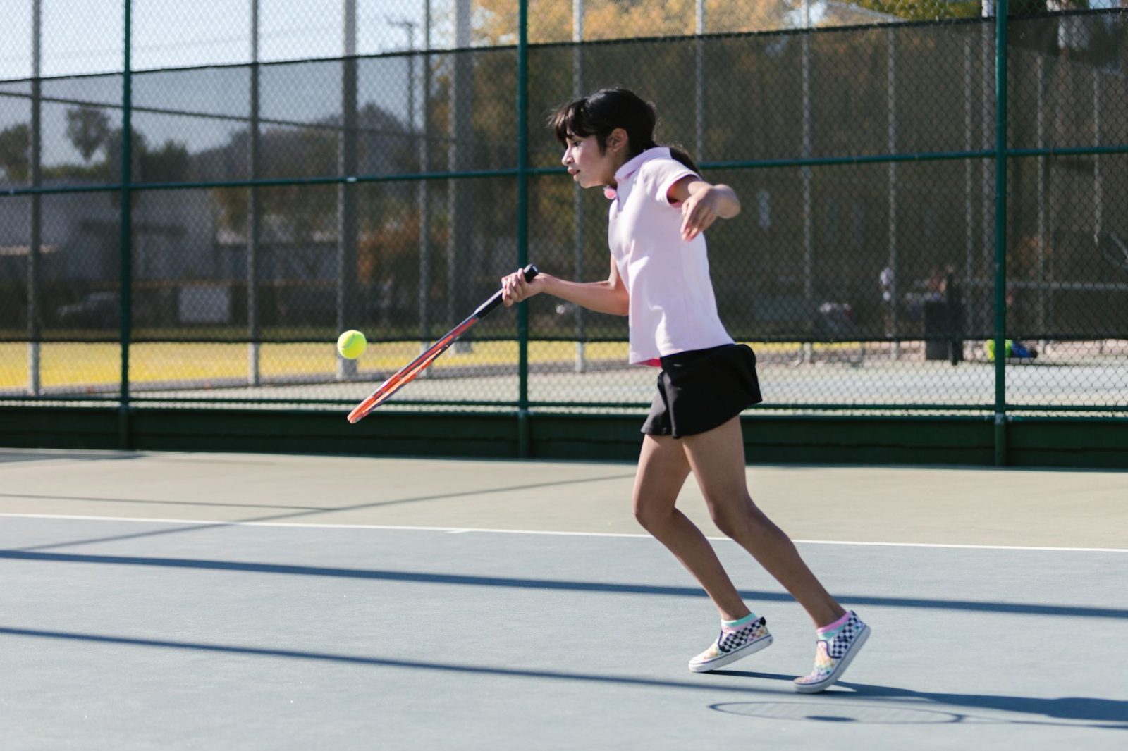 A young player moving forward energetically during a point