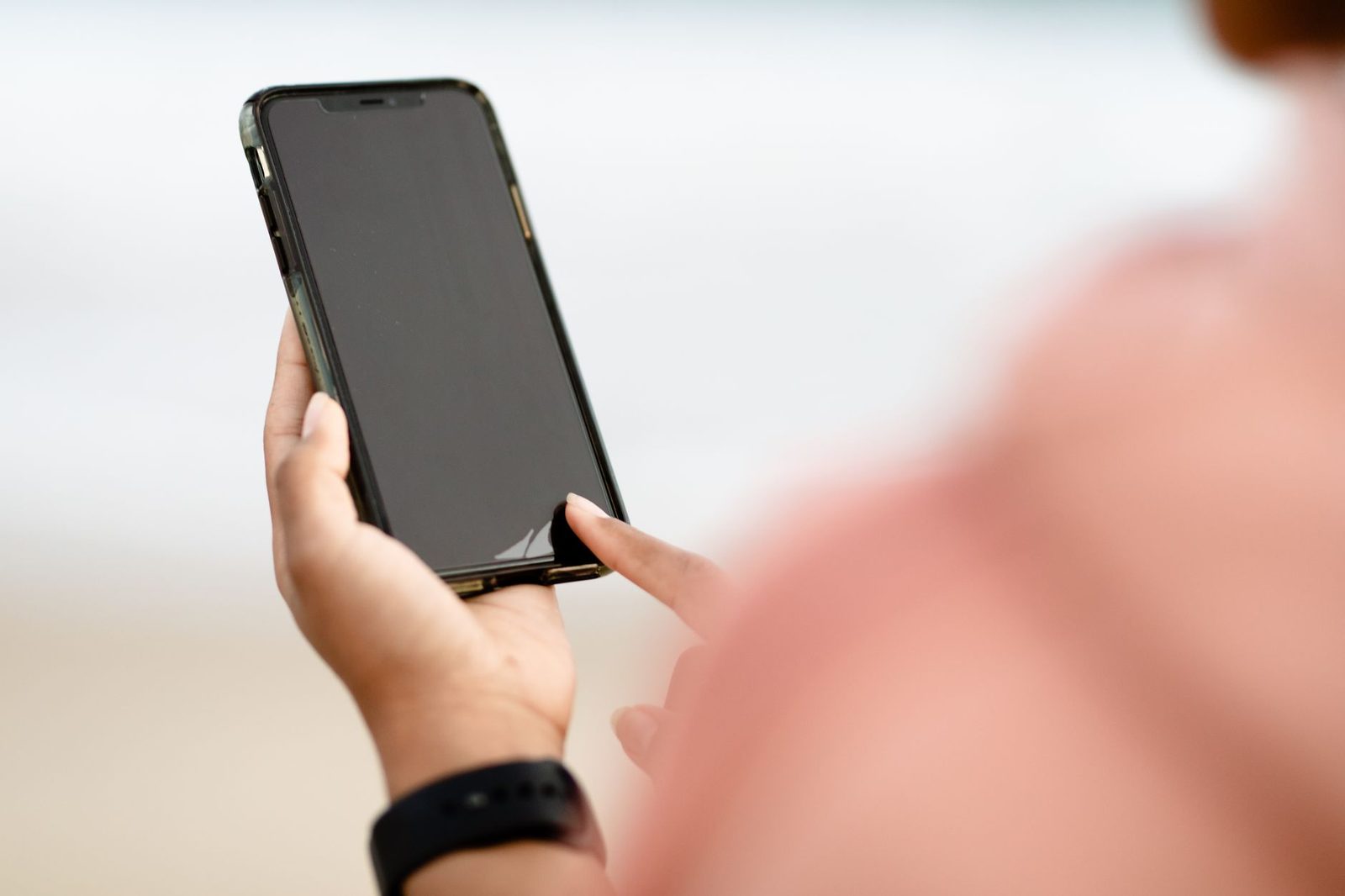 Hand using a smartphone touchscreen outdoors