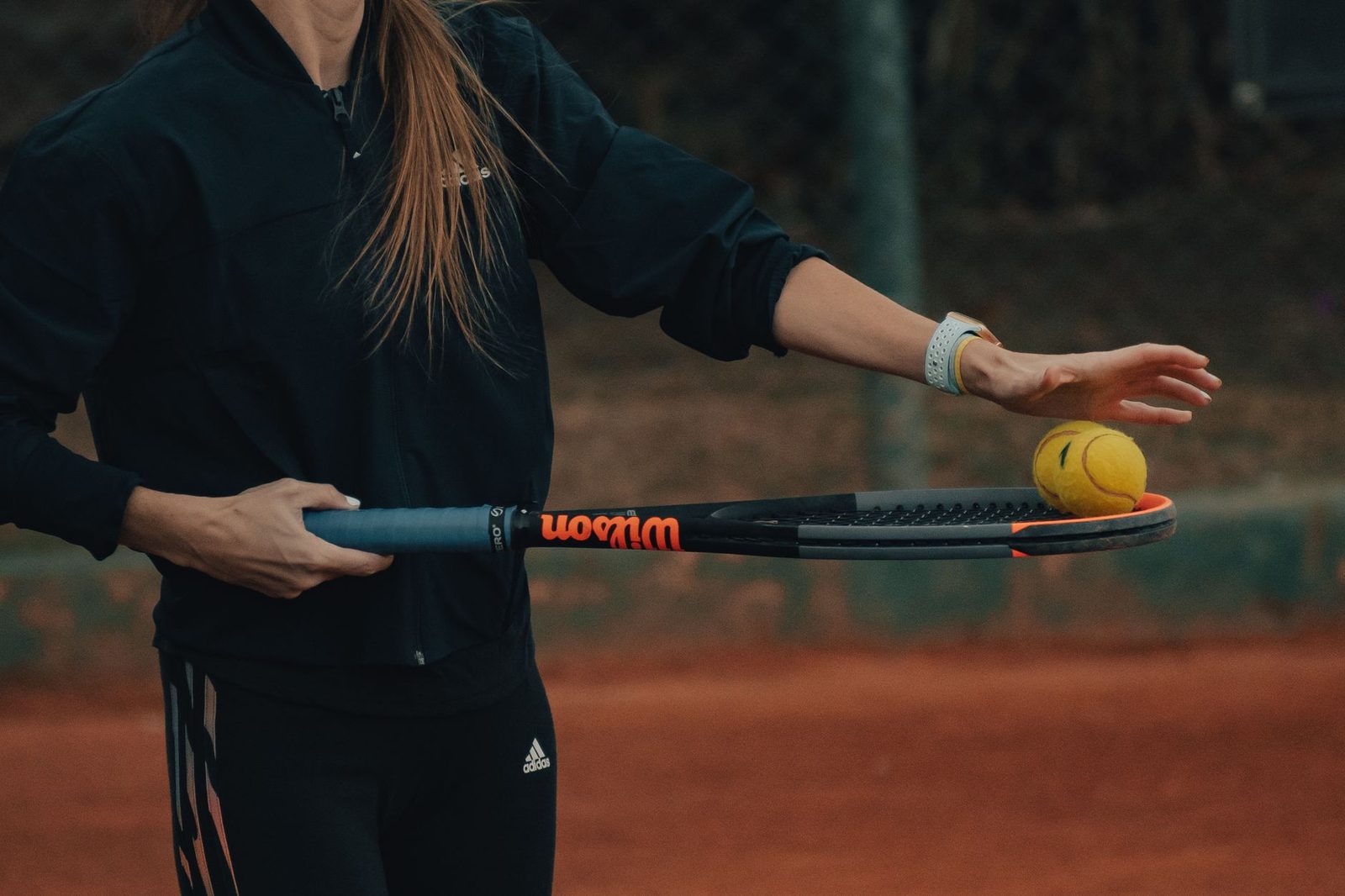 Player practising a controlled backhand on a clay tennis court