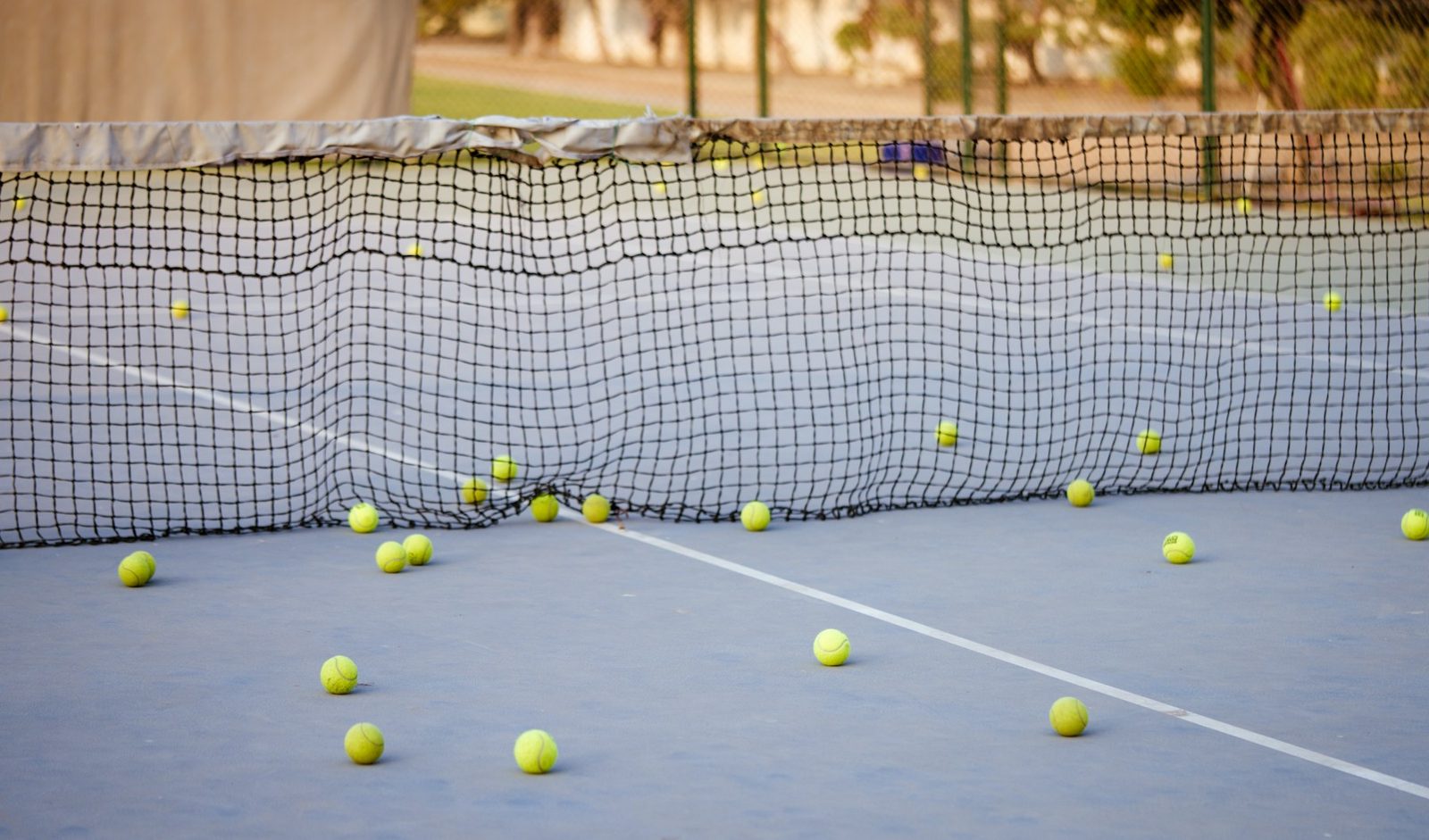 Tennis balls scattered across a court near the net