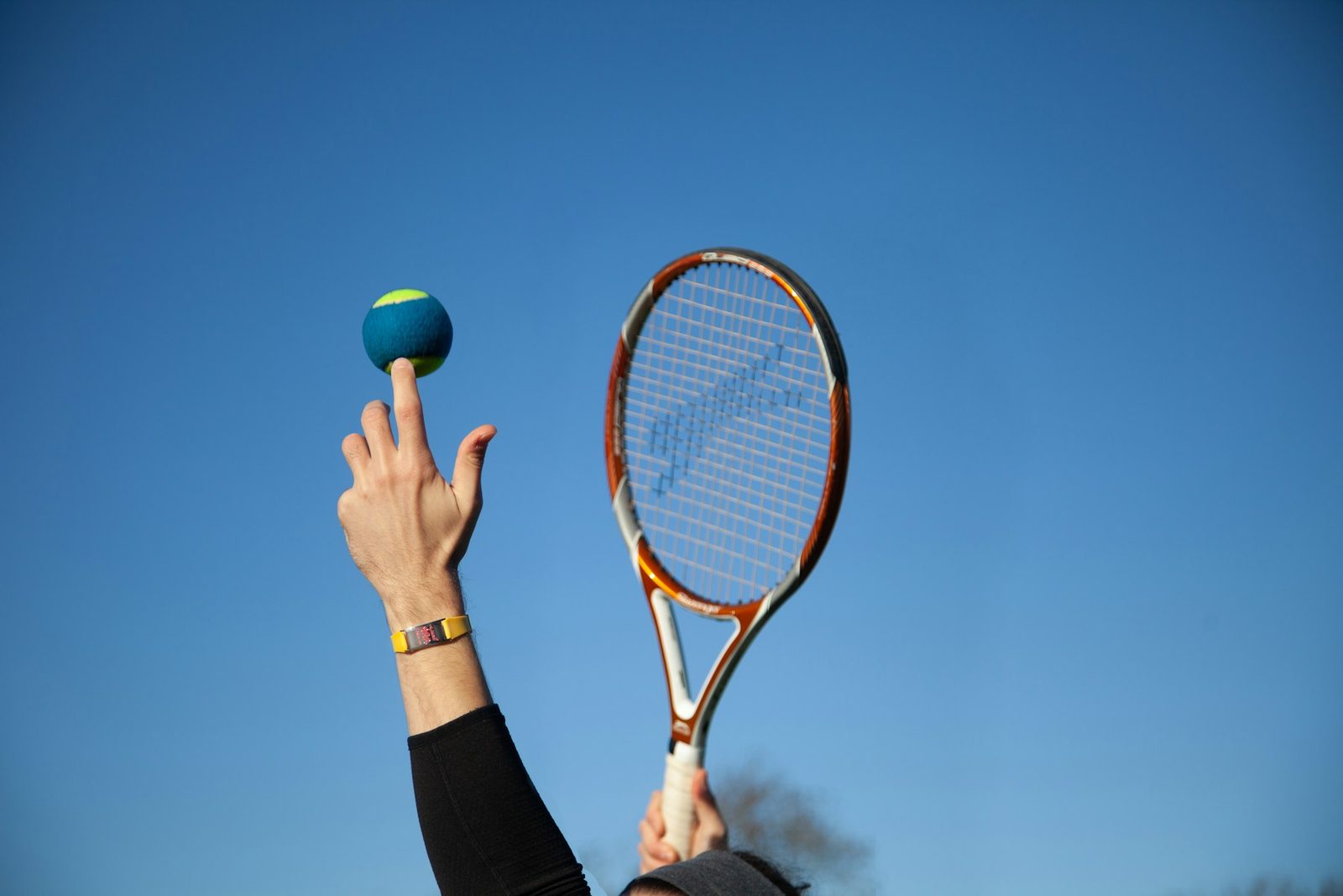 Player holding a red and white tennis racquet ready to begin the service motion