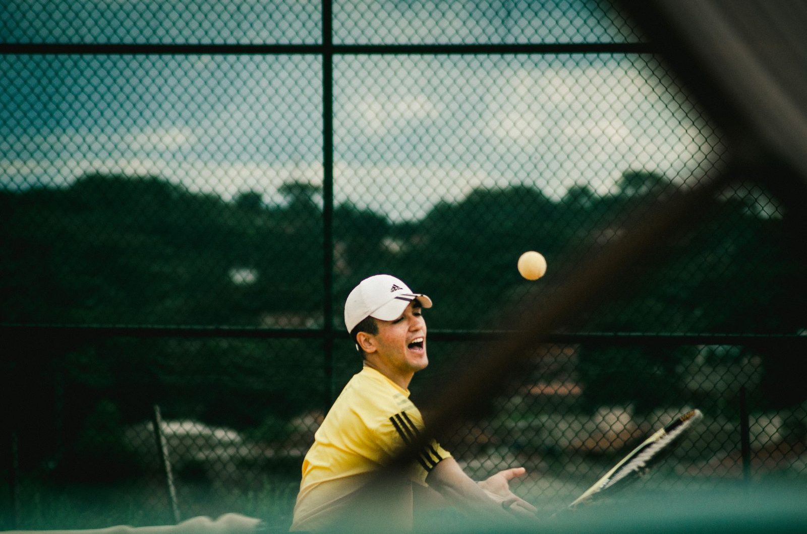 Action shot of a young man striking the ball on an outdoor tennis court