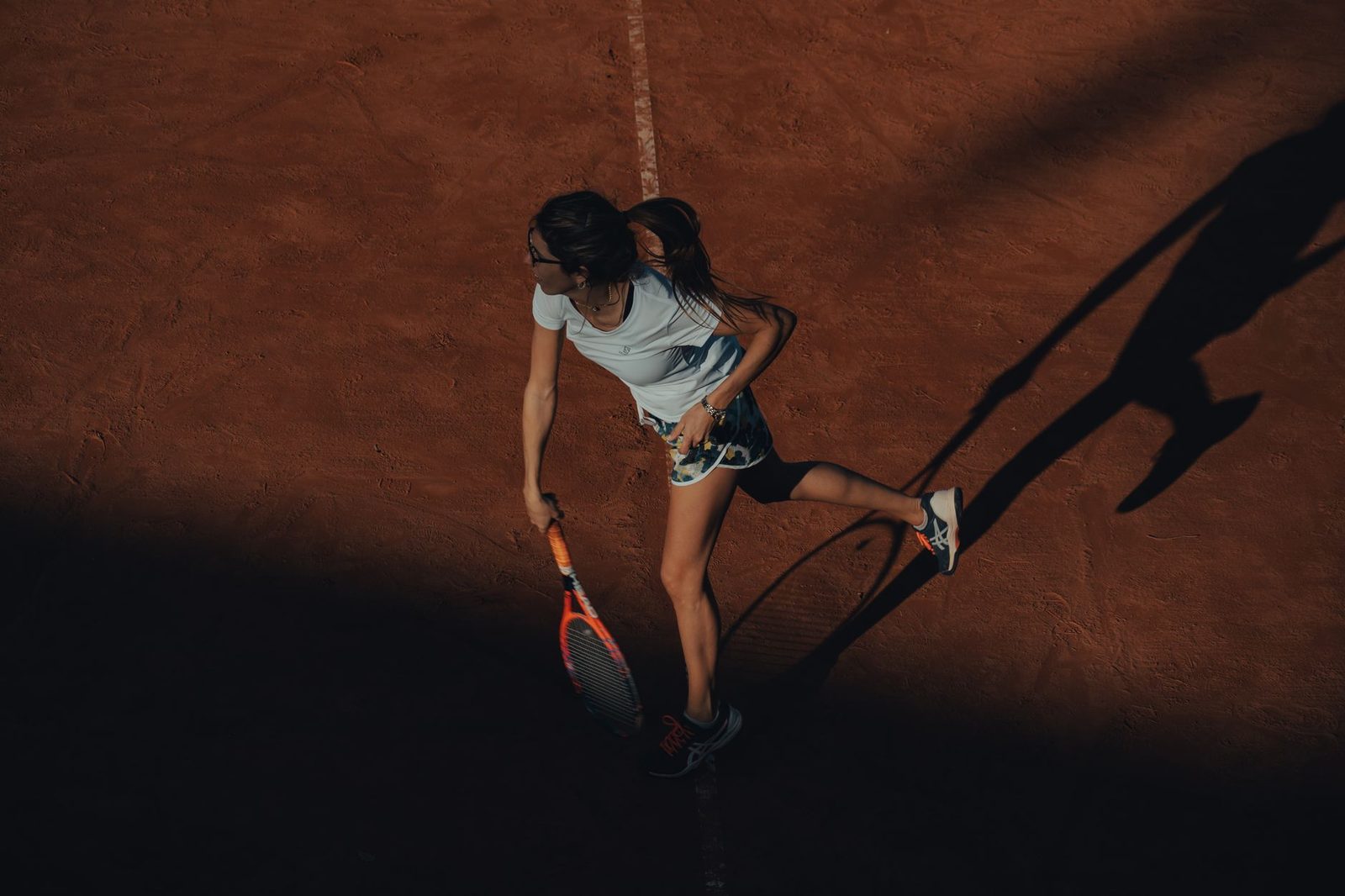 A female tennis player in action on a clay court