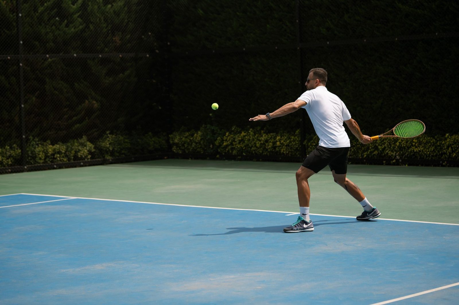 Player hitting a backhand on a sunny outdoor tennis court