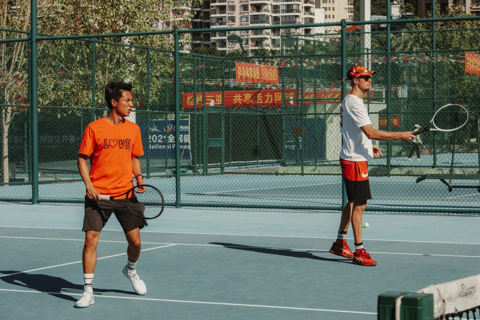 Two people standing on a tennis court holding racquets
