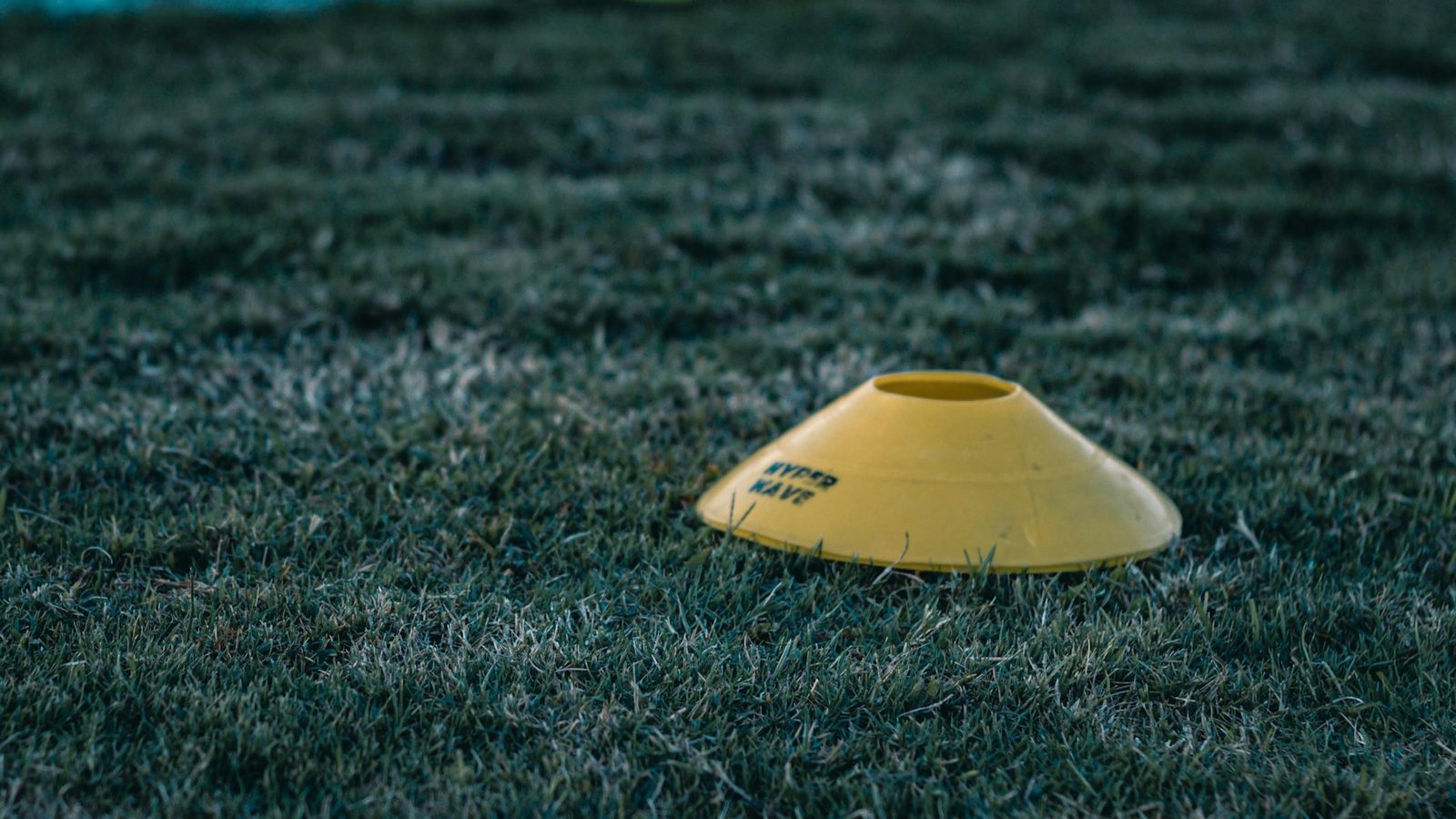 A yellow disc cone on grass, the basic marker used for court movement drills