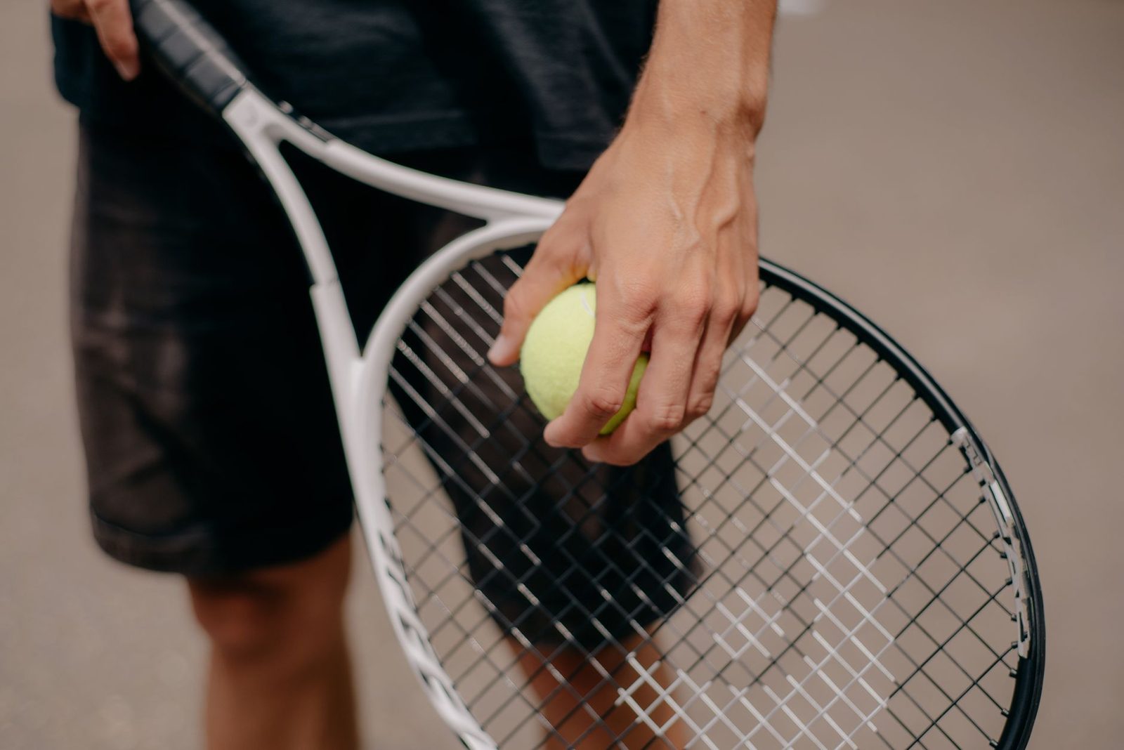 Close view of a player holding the ball and racquet while preparing to serve