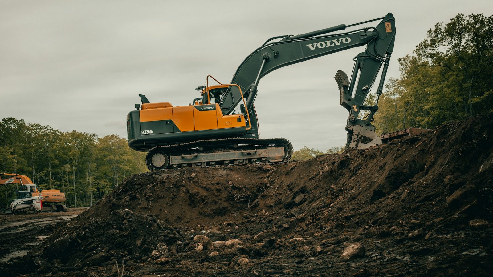 Orange and white excavator levelling bare brown ground on a construction site