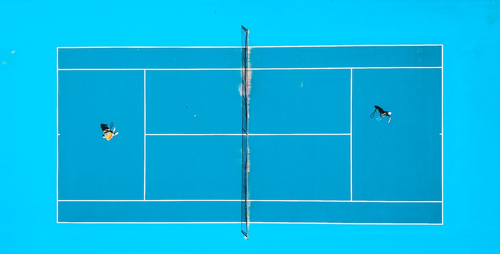 Aerial view of two players covering a tennis court from the back