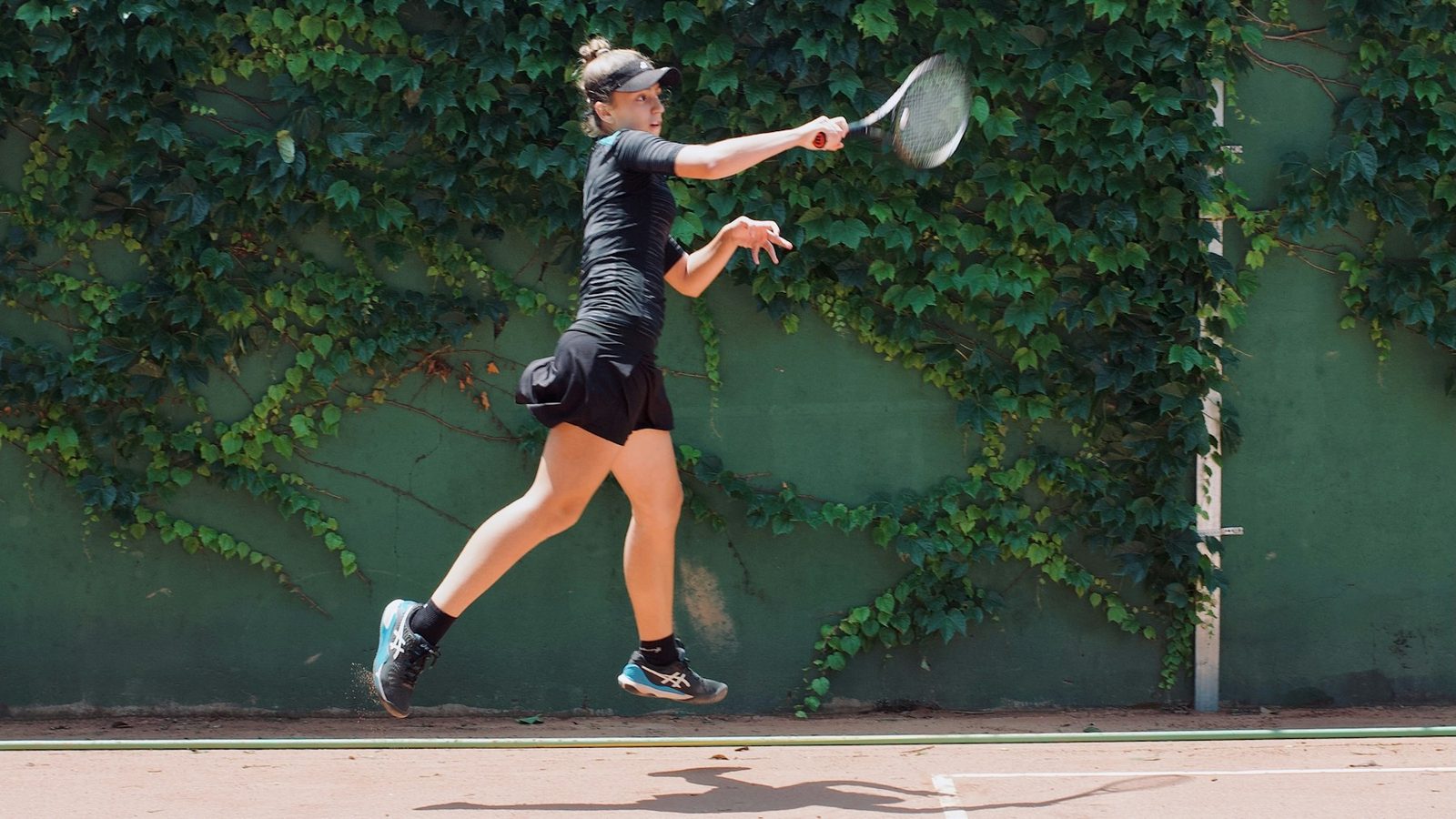 Player reaching up to strike a high ball during a tennis point