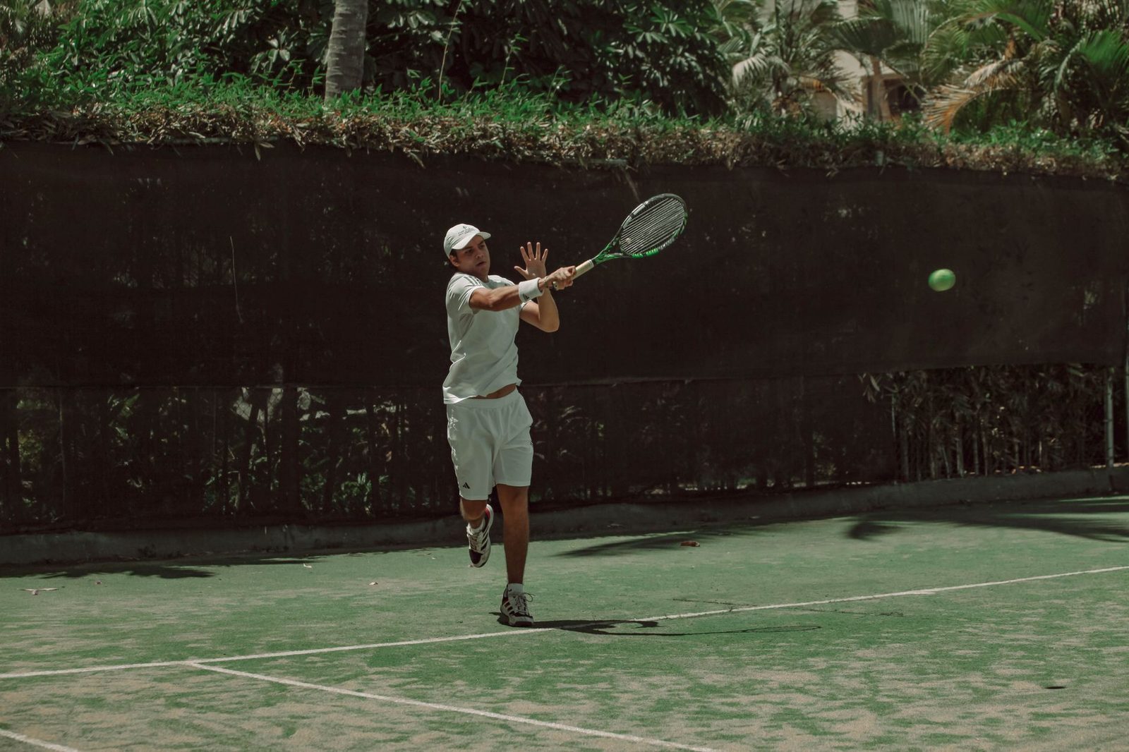 Male tennis player hitting a forehand on an outdoor court on a sunny day