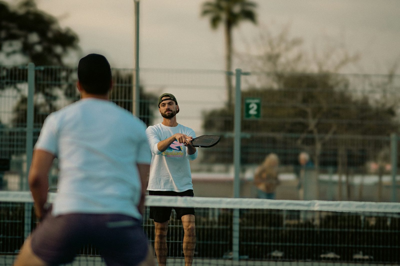 Two men playing a singles match on an outdoor tennis court