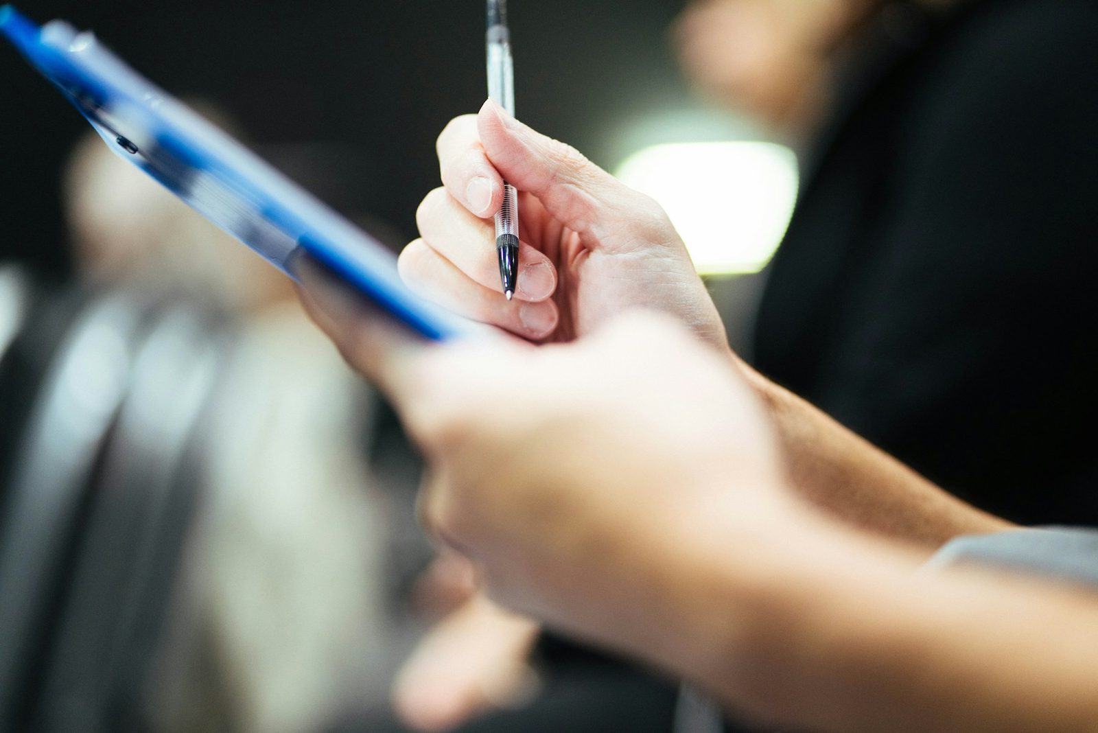 A hand holding a pen over a clipboard