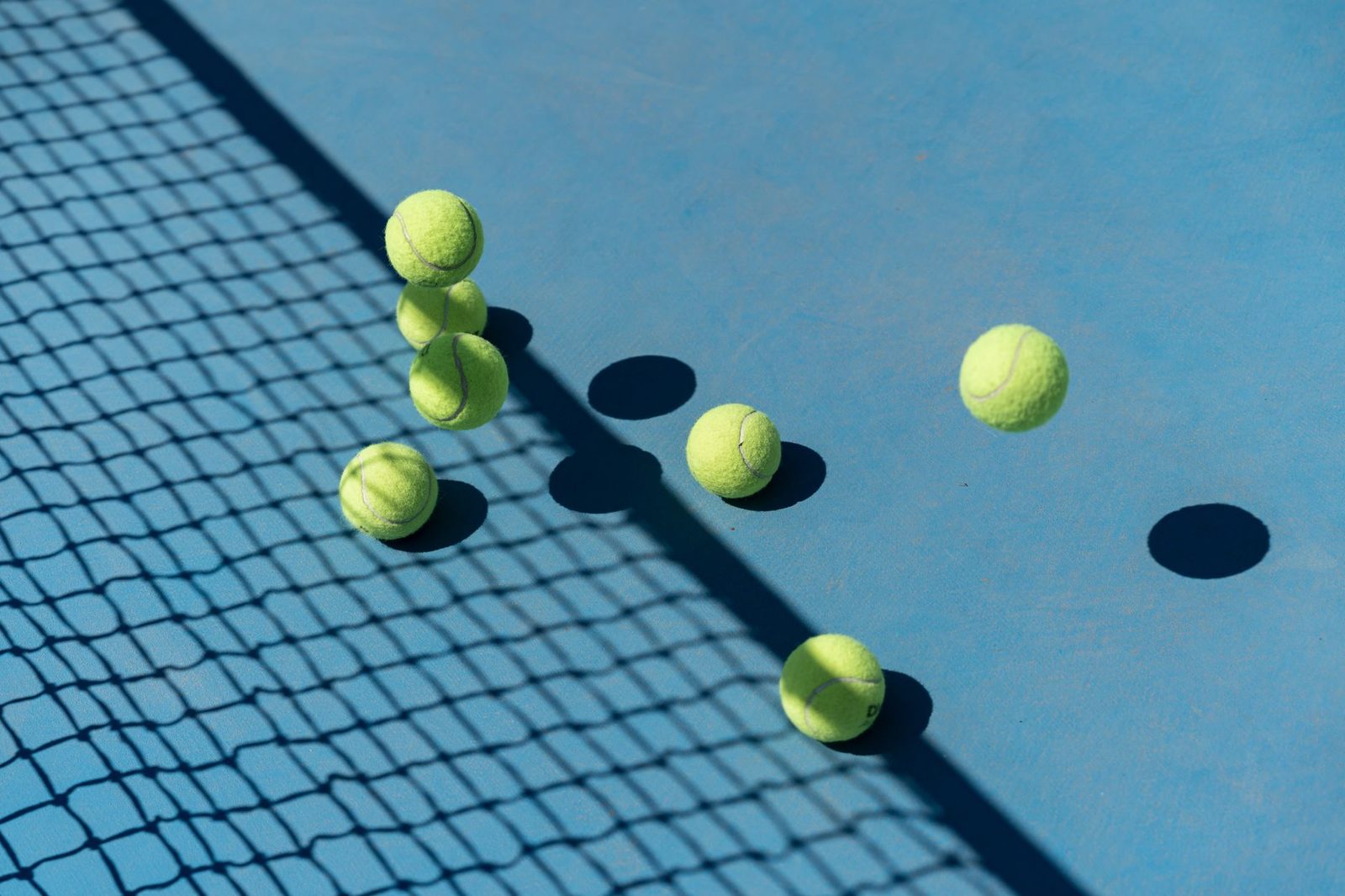 Tennis balls scattered on a blue court, seen from above