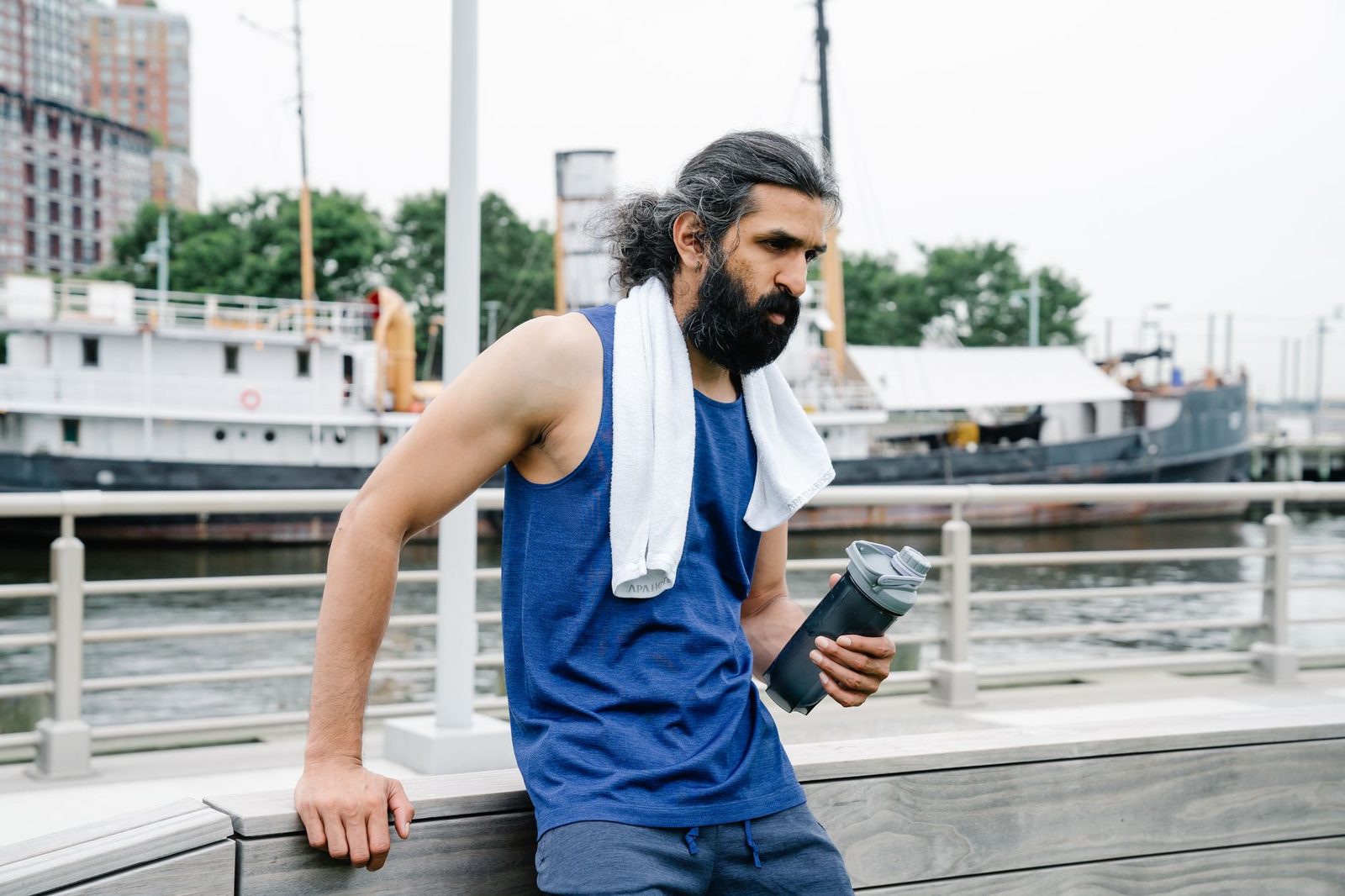 A man with a towel and water bottle resting after exercise