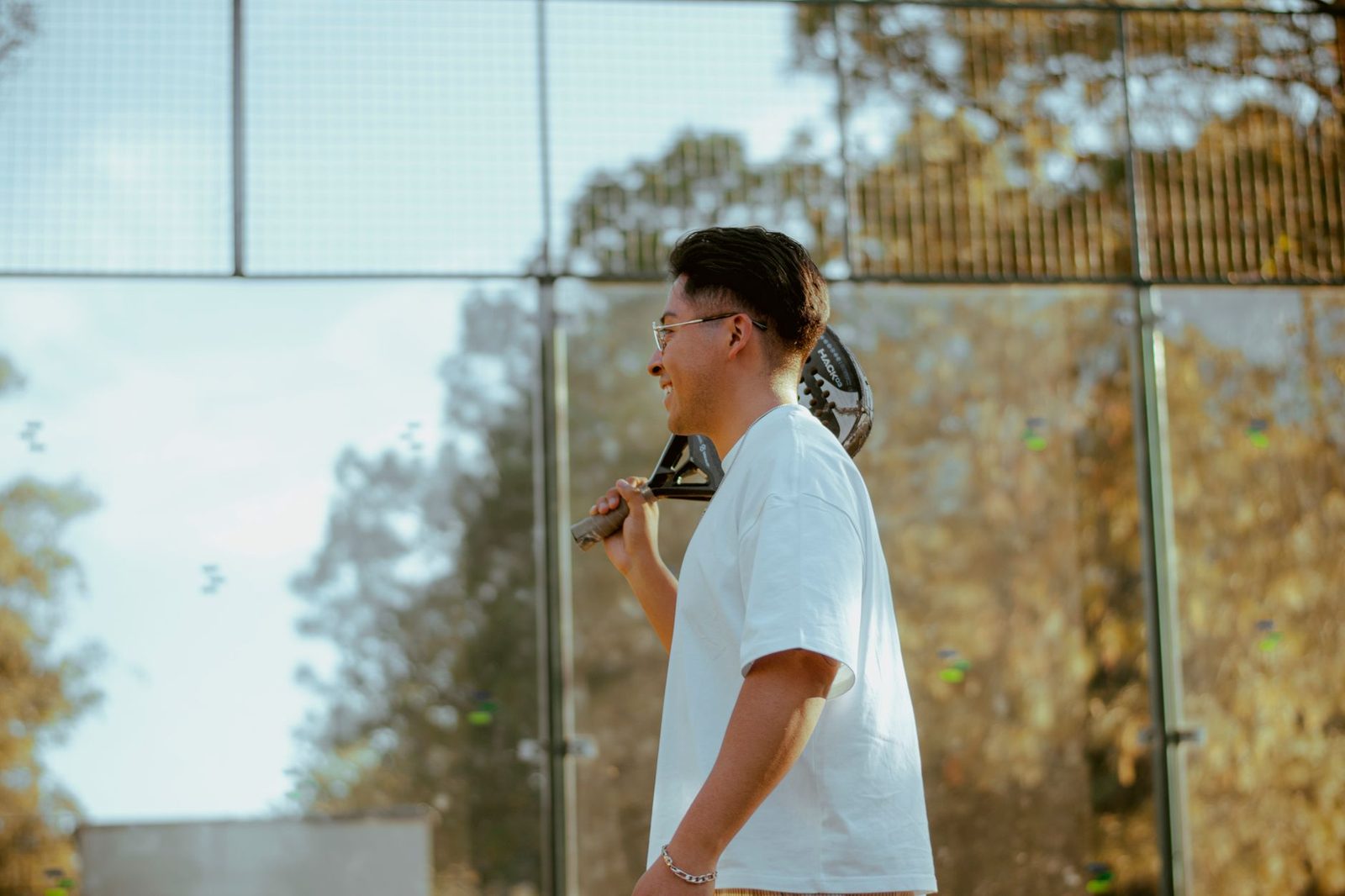 Young man standing outdoors holding a padel racket
